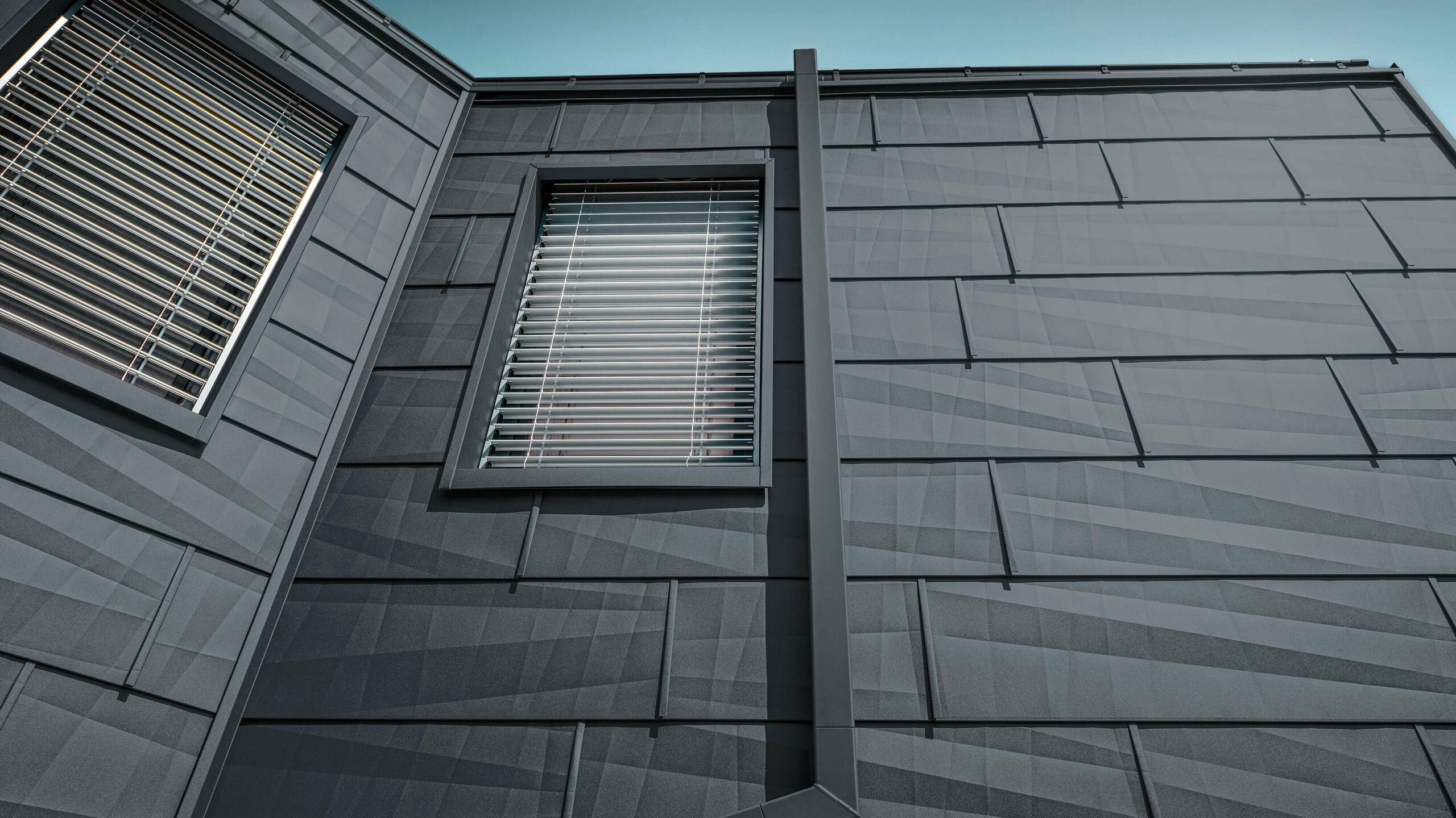 Fasad täckt med PREFA fasadpanel FX.12 i antracit, aluminiumfasadpaneler med det rektangulära stupröret, kvadratröret, i antracit från PREFA.