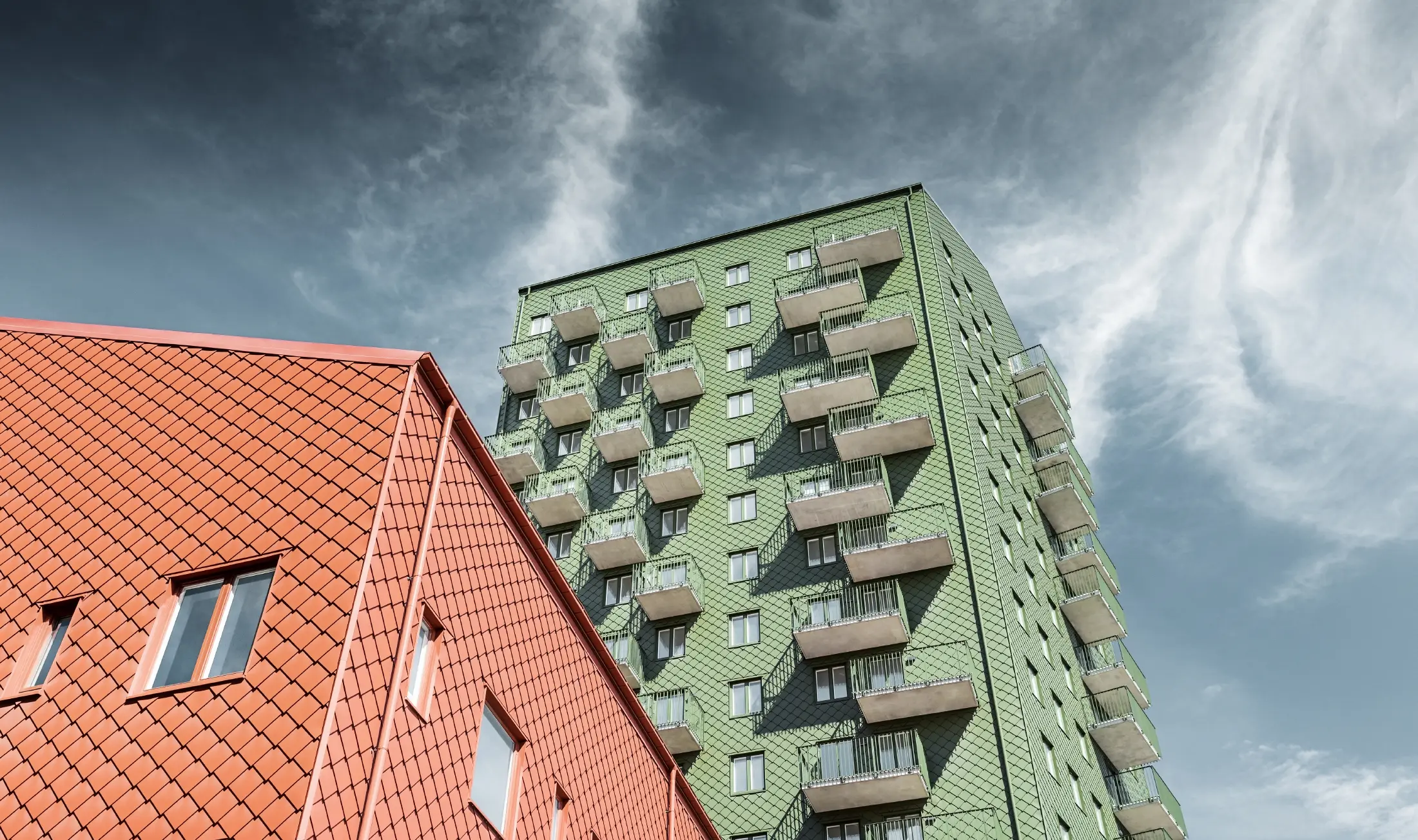 Höghus med balkonger med fasadgestaltning med PREFA väggromb 29 × 29 i olivgrön och tegelröd