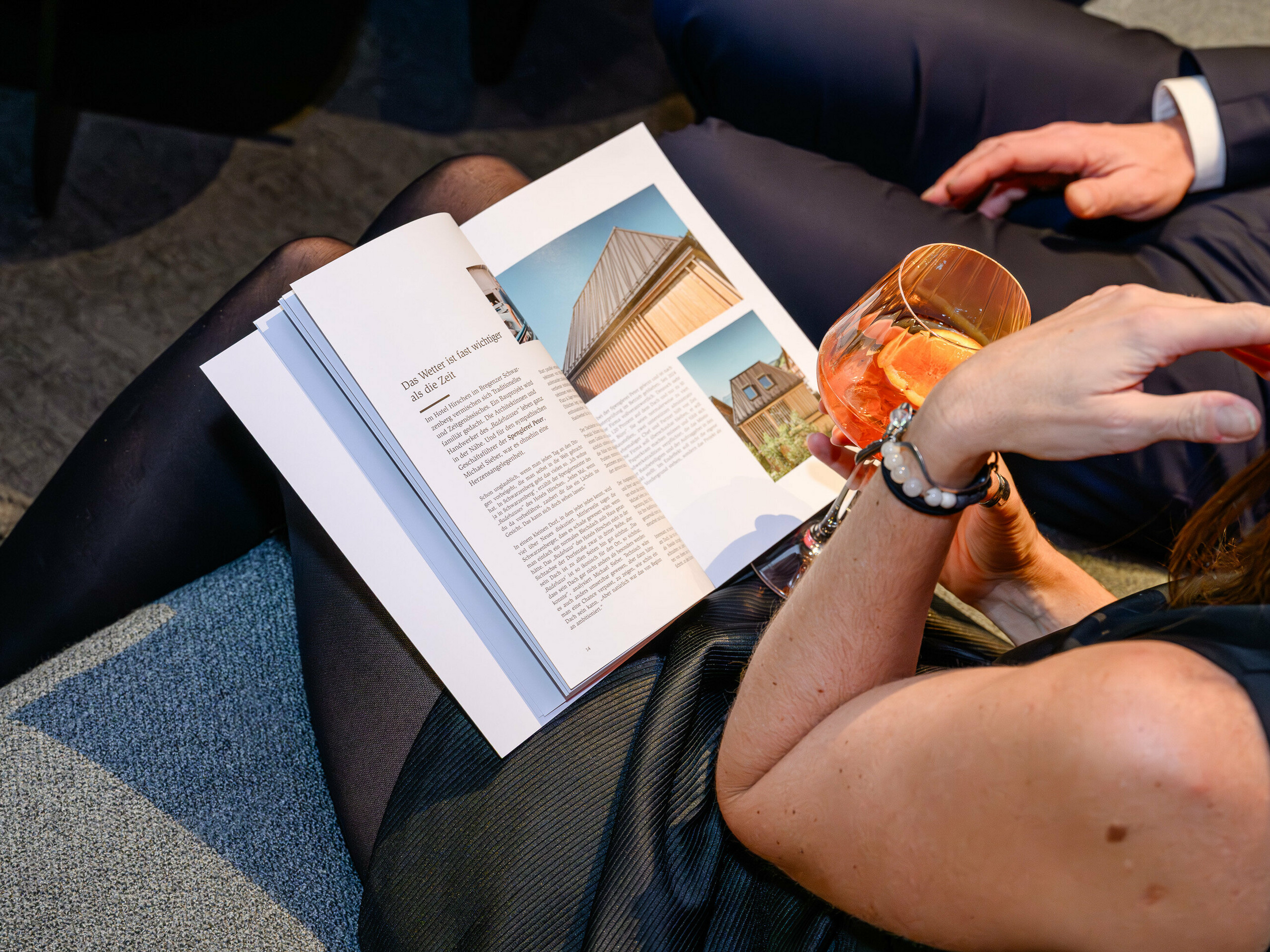 Stimmungsvolle Szene auf der PREFARENZEN Präsentation 2026 im k47.wien: Eine elegante Frau blättert mit einem Drink in der Hand durch das neue PREFA Architekturbuch – ein Eyecatcher voller Designinspiration. Sichtbar ist ein Objekt mit PREFALZ, das mit modernem Aluminium-Charakter beeindruckt. Das Bild transportiert Genuss, Austausch und Neugier auf Innovationen. Die hochwertige PREFA Oberfläche vereint Ästhetik und Langlebigkeit – perfekt für kreative Architekturideen. Aluminium von PREFA setzt Maßstäbe und begeistert Profis wie Planer, Architekten und Verarbeiter gleichermaßen.