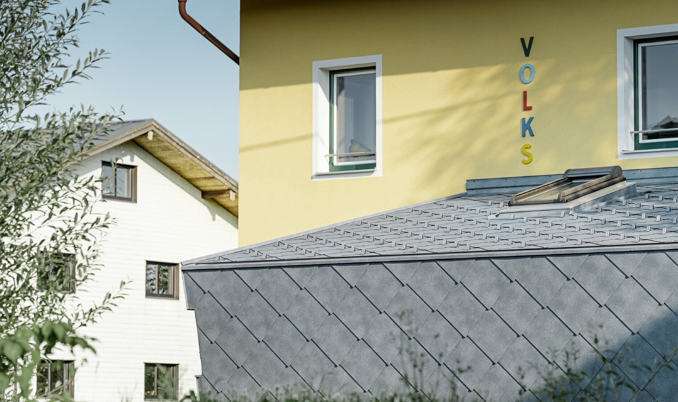 Tillbyggnad på en folkskola täckt med tak- och väggromber av aluminium från PREFA i stengrått