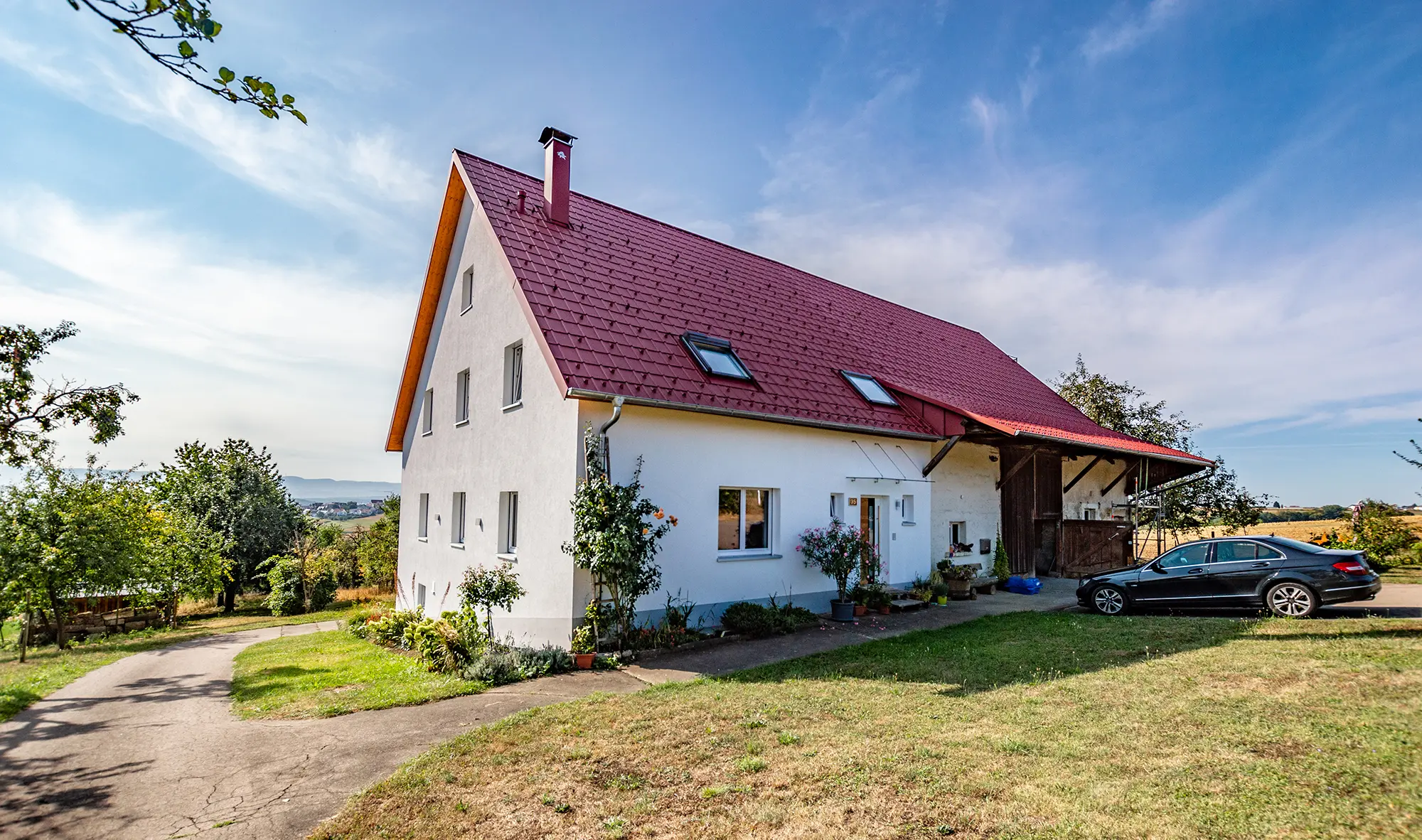 Gammal liten gård på landet, vackert renoverad med PREFA takplattor i oxidrött.