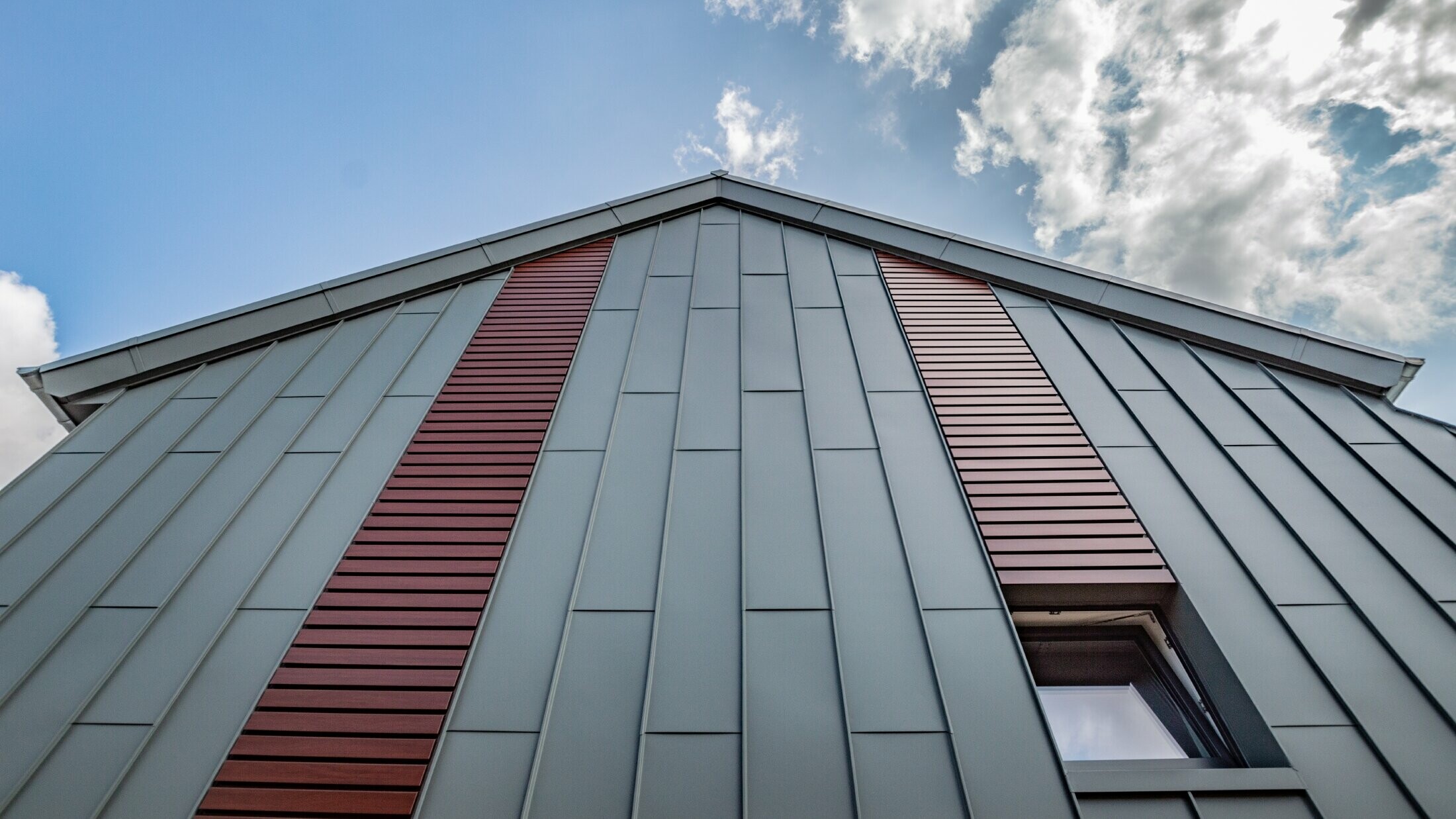Vertikal fasad med stående vinkelfals med skivtäckning i ljusgrå och liggande fasad i mörkt trä från PREFA.