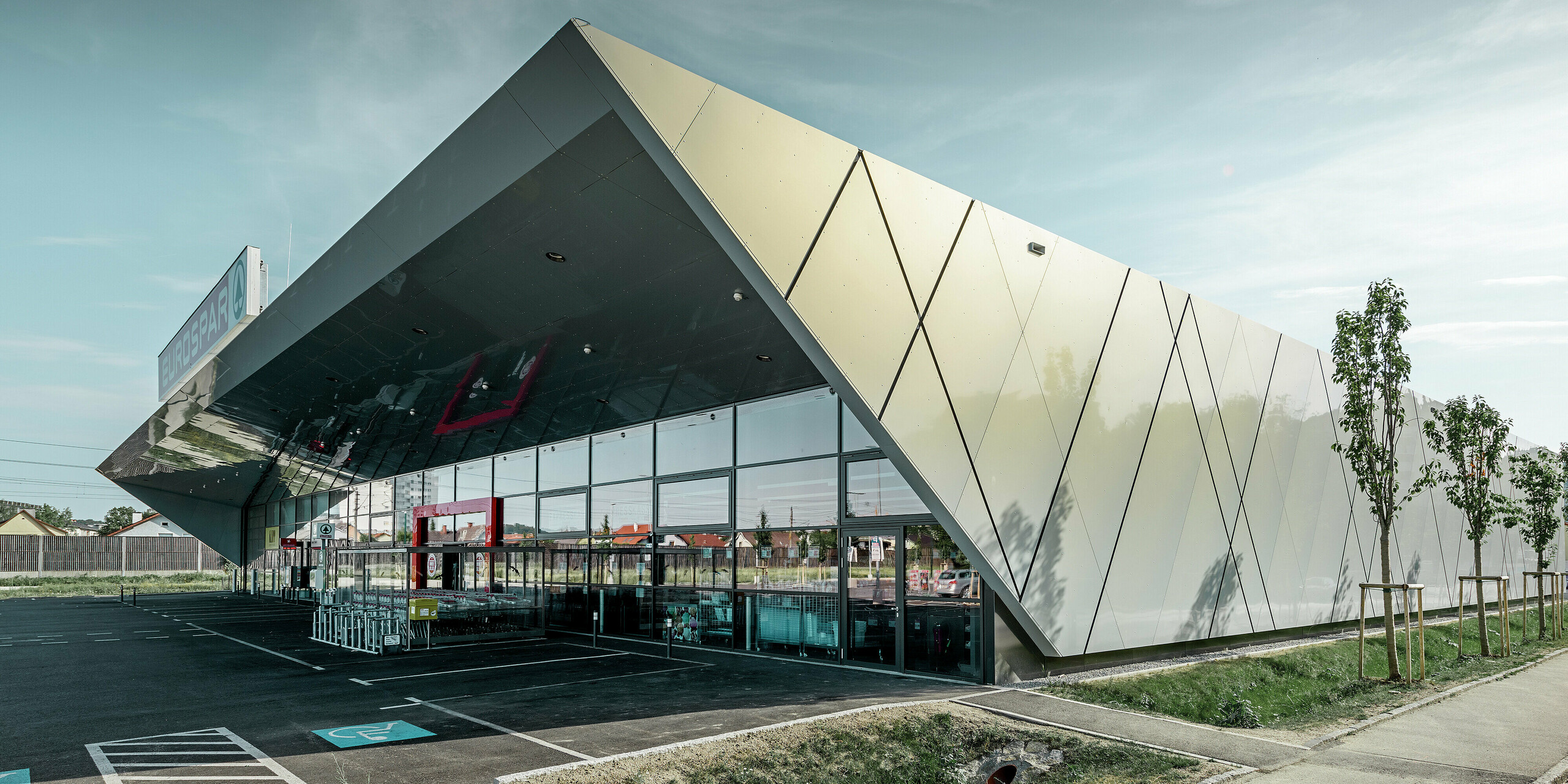 Ingången till den nya Eurospar filialen i Wels med den moderna fasadpanelen från PREFA i silverguld. Fasaden av aluminiumkomposit skimrar i solen i varierande färger beroende på betraktningsvinkeln.