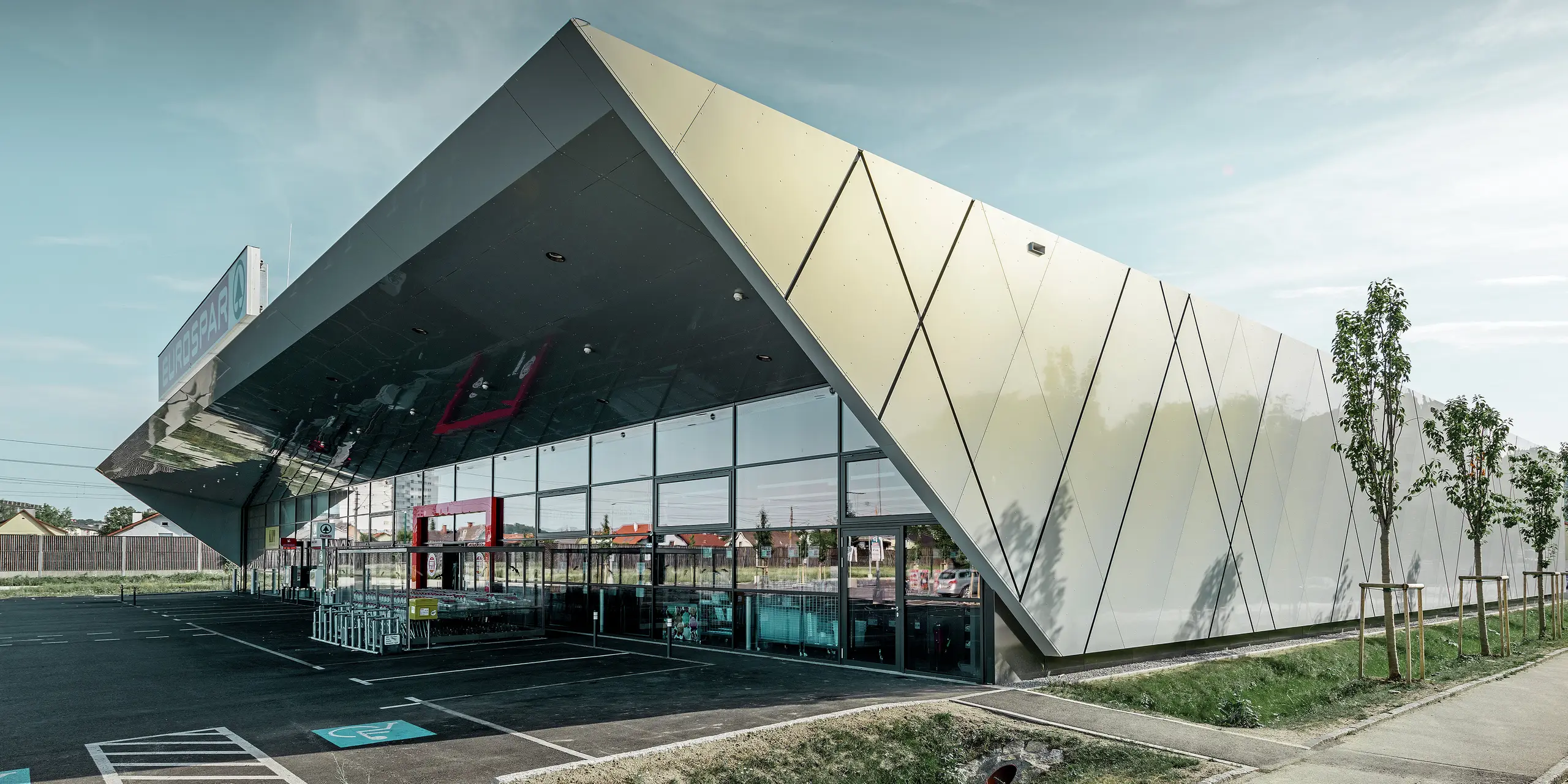 Ingången till den nya Eurospar filialen i Wels med den moderna fasadpanelen från PREFA i silverguld. Fasaden av aluminiumkomposit skimrar i solen i varierande färger beroende på betraktningsvinkeln.