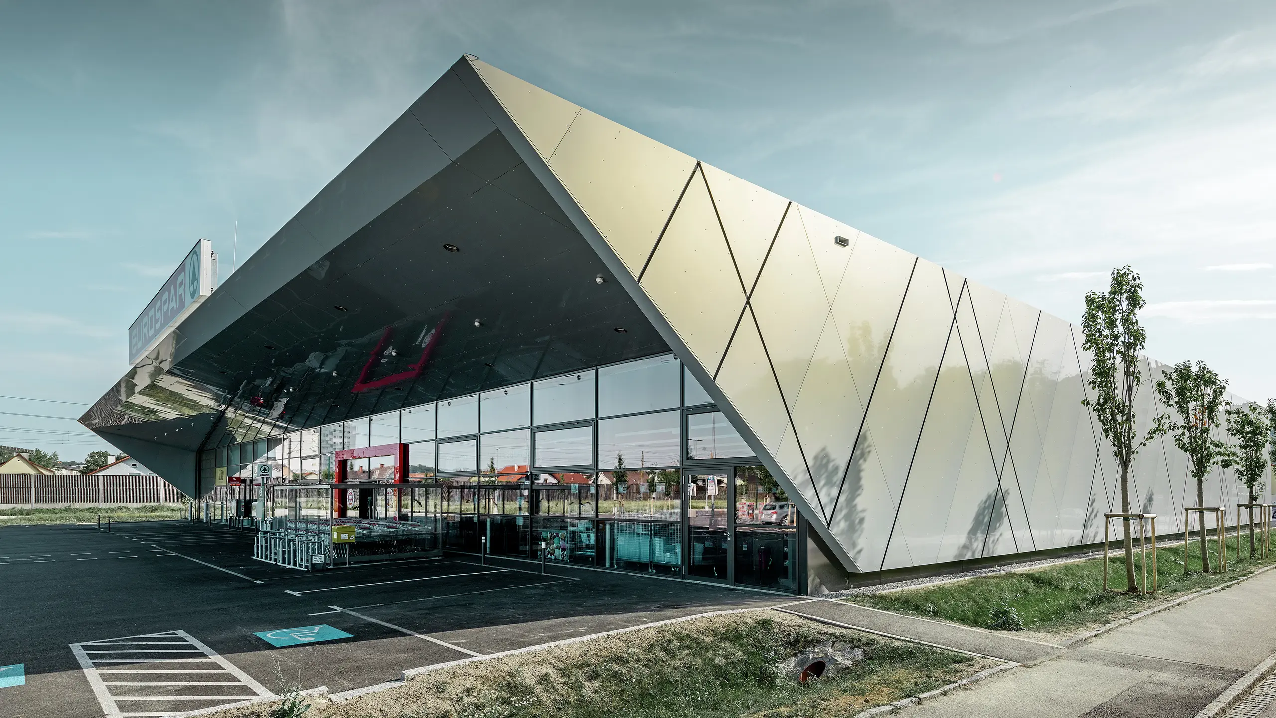 Ingången till den nya Eurospar filialen i Wels med den moderna fasadpanelen från PREFA i silverguld. Fasaden av aluminiumkomposit skimrar i solen i varierande färger beroende på betraktningsvinkeln.