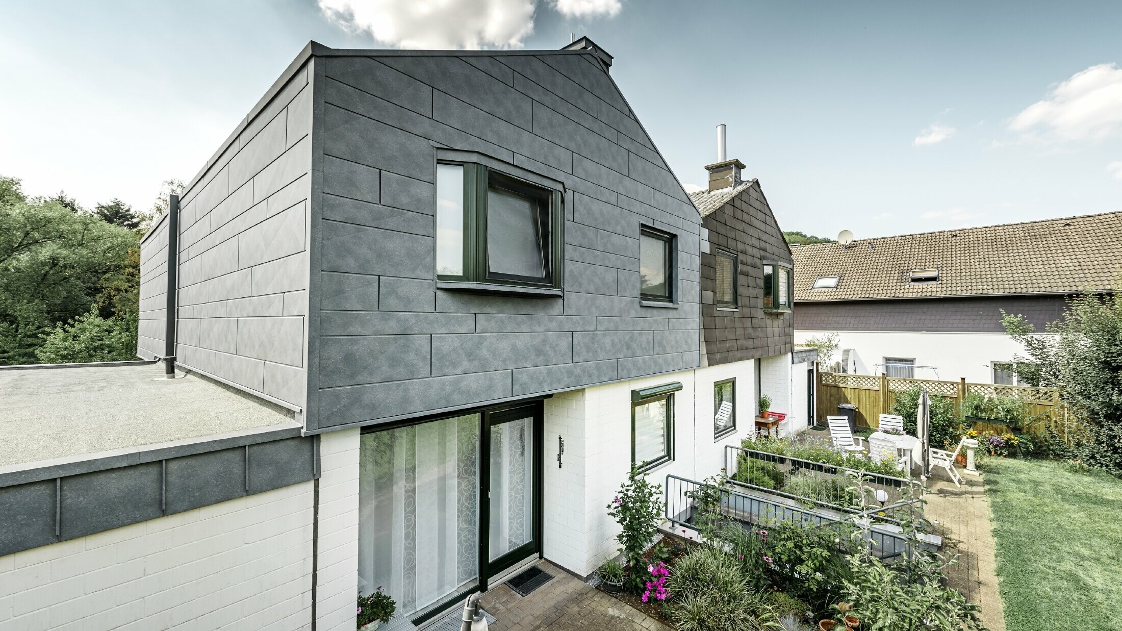 Den övre delen av byggnaden i parhuset renoverades med PREFA fasadkomponenter Siding.X i P.10 stengrå. Bredvid, för att jämföra hushalvan före renoveringen.