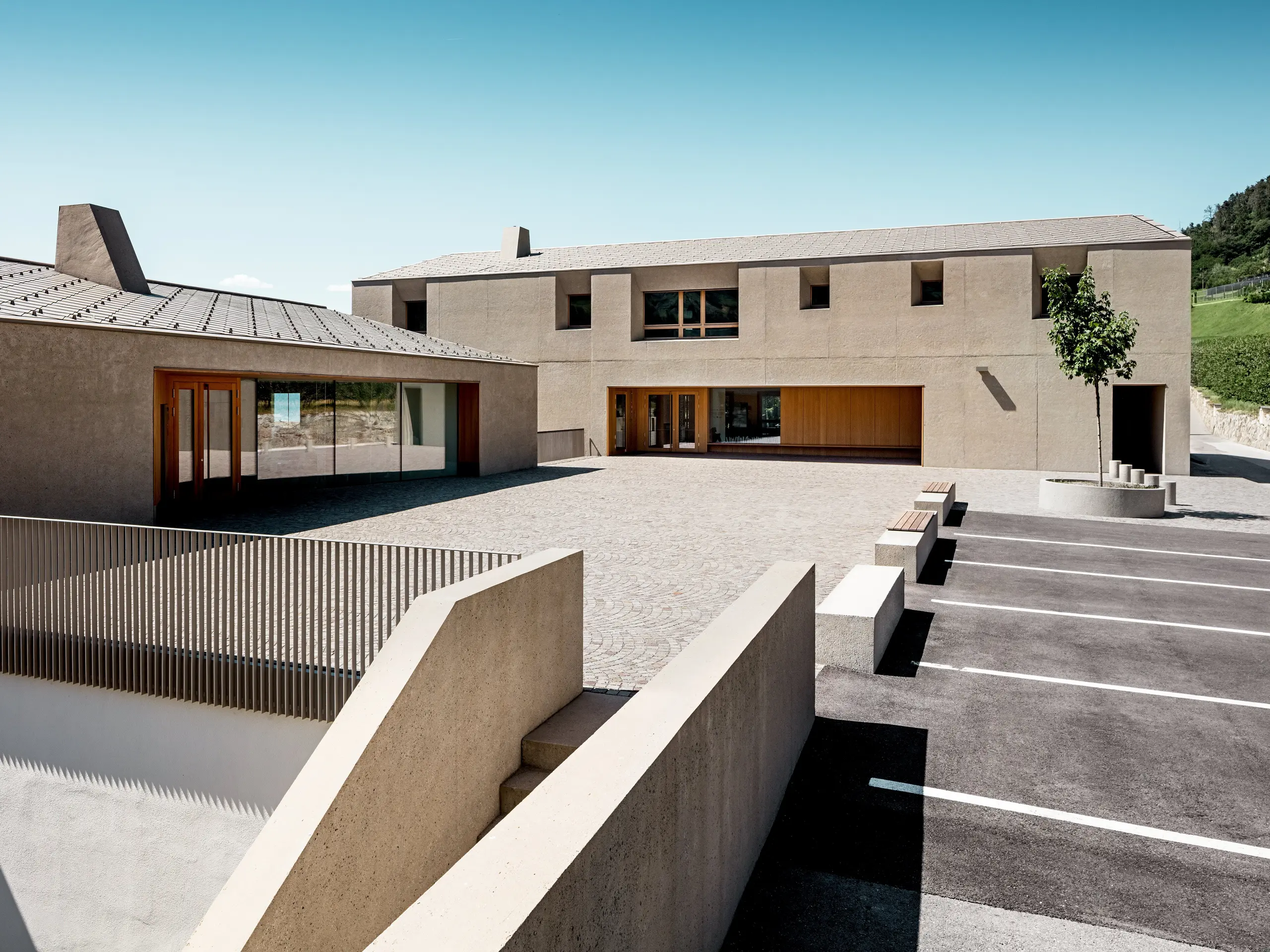 Das Bildungszentrum Riffian in Südtirol verbindet moderne Architektur mit präziser Dachgestaltung. Die zwei Baukörper mit PREFA Dachrauten 44 × 44 in P.10 Bronze fügen sich harmonisch in die Landschaft ein. Die langlebige Aluminiumdeckung sorgt für zuverlässigen Witterungsschutz und unterstreicht die klare Formensprache des Schulgebäudes.