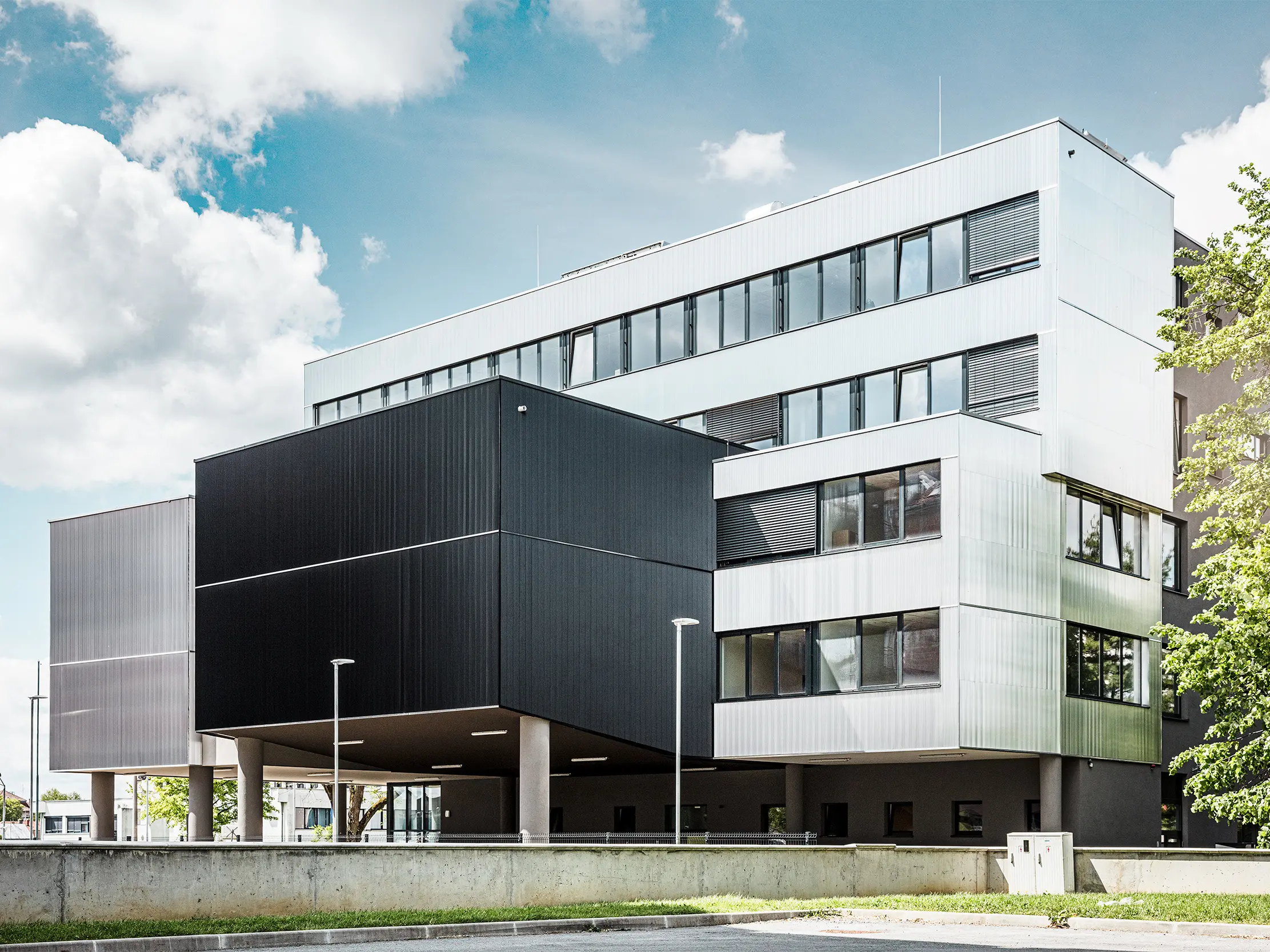Sidovy av musikhögskolan i Bjevolar med en PREFA-fasad med sicksackprofil. Fasaden är utformad i svart och ljust aluminium. De geometriska formerna skapar en slående, minimalistisk design.