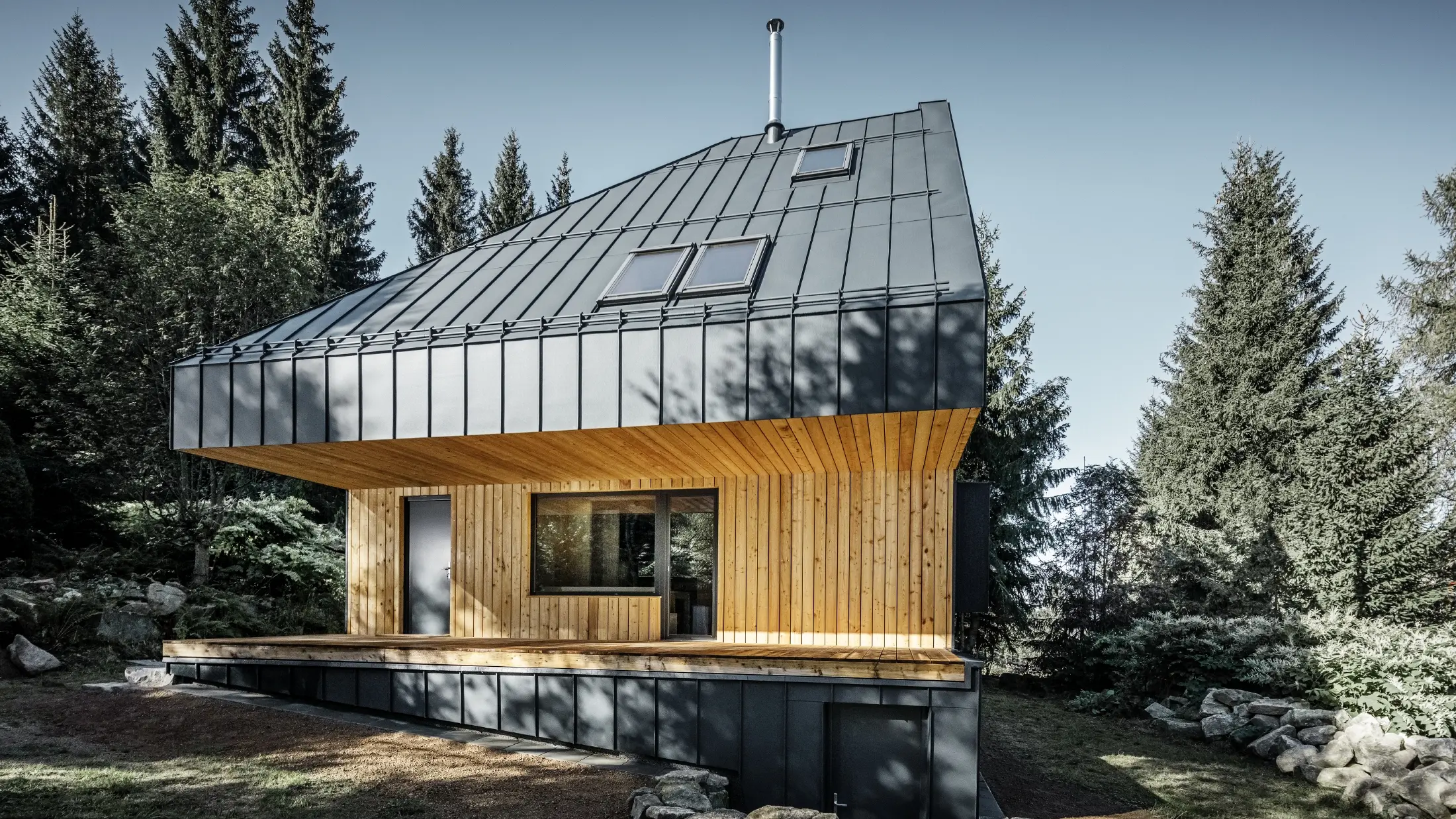 Arkitektoniskt enfamiljshus i skogen, det imponerande taket kläddes med PREFA Prefalz aluminium i antracit. Takbjälklaget och fasaden är klädda med träpaneler.