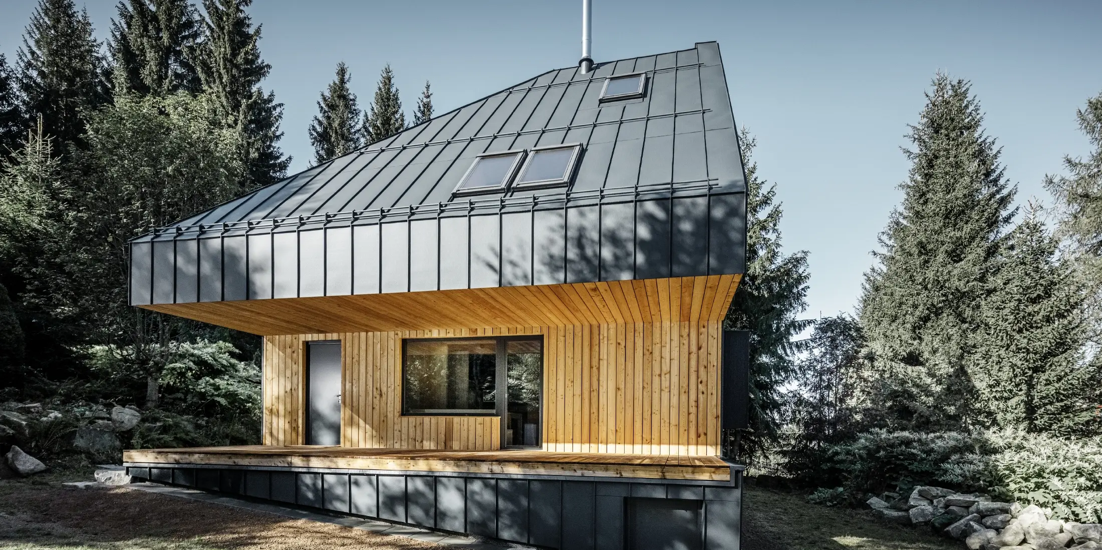 Arkitektoniskt enfamiljshus i skogen, det imponerande taket kläddes med PREFA Prefalz aluminium i antracit. Takbjälklaget och fasaden är klädda med träpaneler.