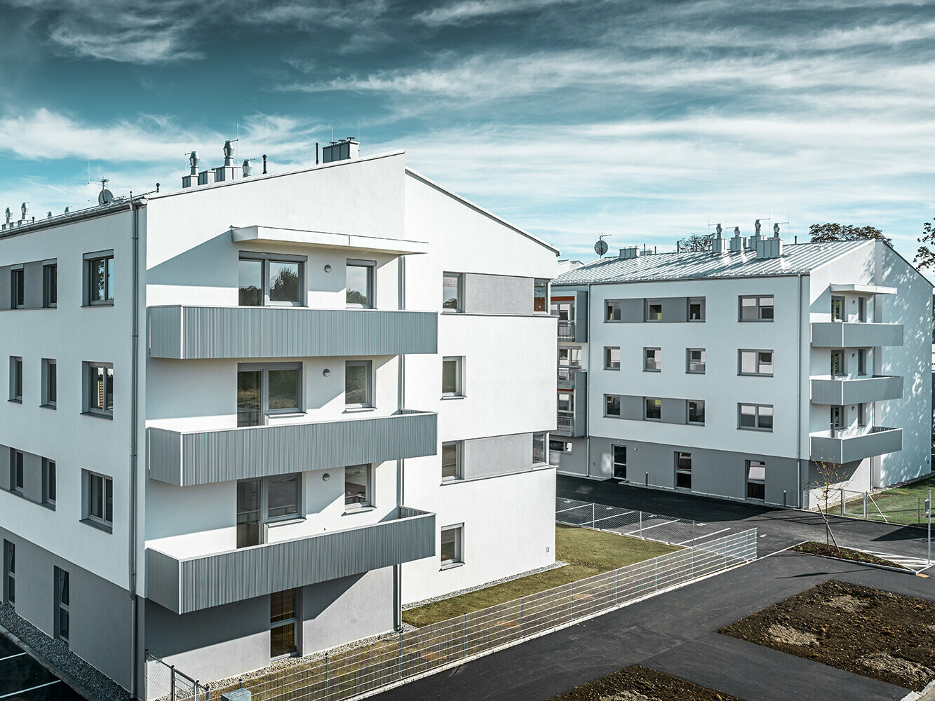 Modernt bostadshus med vit fasad och balkonger med PREFA sicksackprofil i silvermetallic