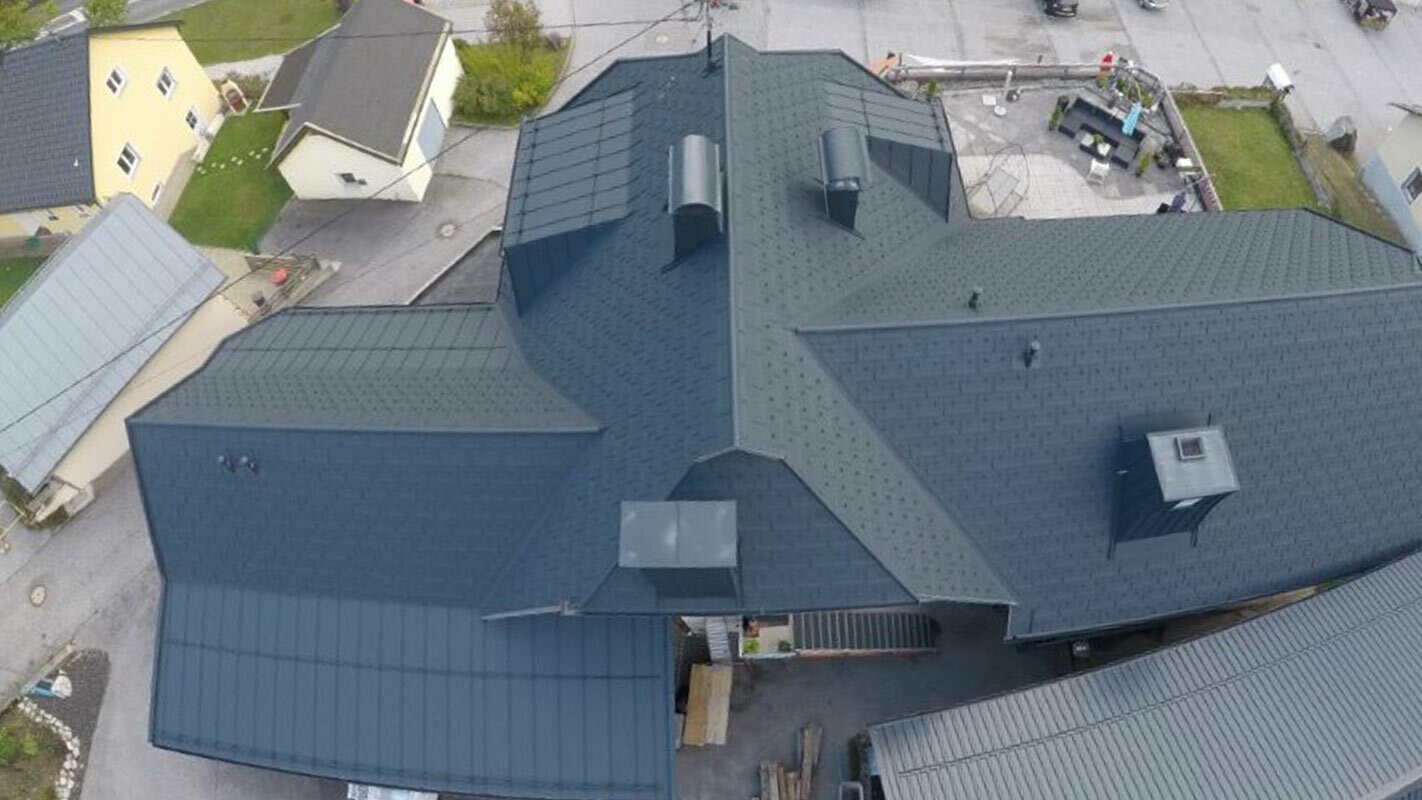 Takrenovering av ett stort takområde med många detaljer - Vinkelrännor, takkupor och skorstenar. Taket är täckt med aluminiumtakplattor R.16 av PREFA i antracit.