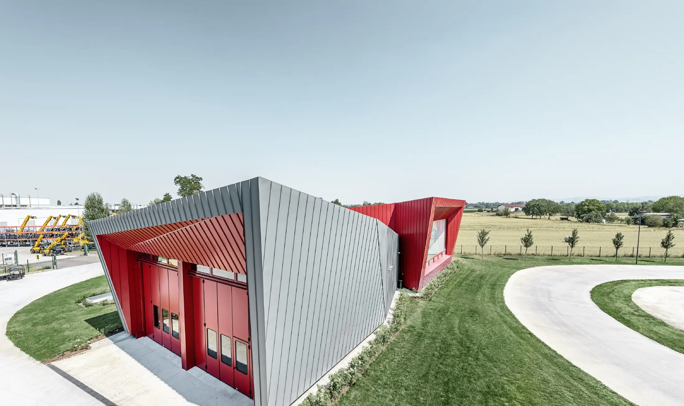 modernt träningscenter av Dieci i Montecchio Emilia,Italien, med tribun med aluminiumfasad med prefalz i ljusgrått och falzonal i karminrött