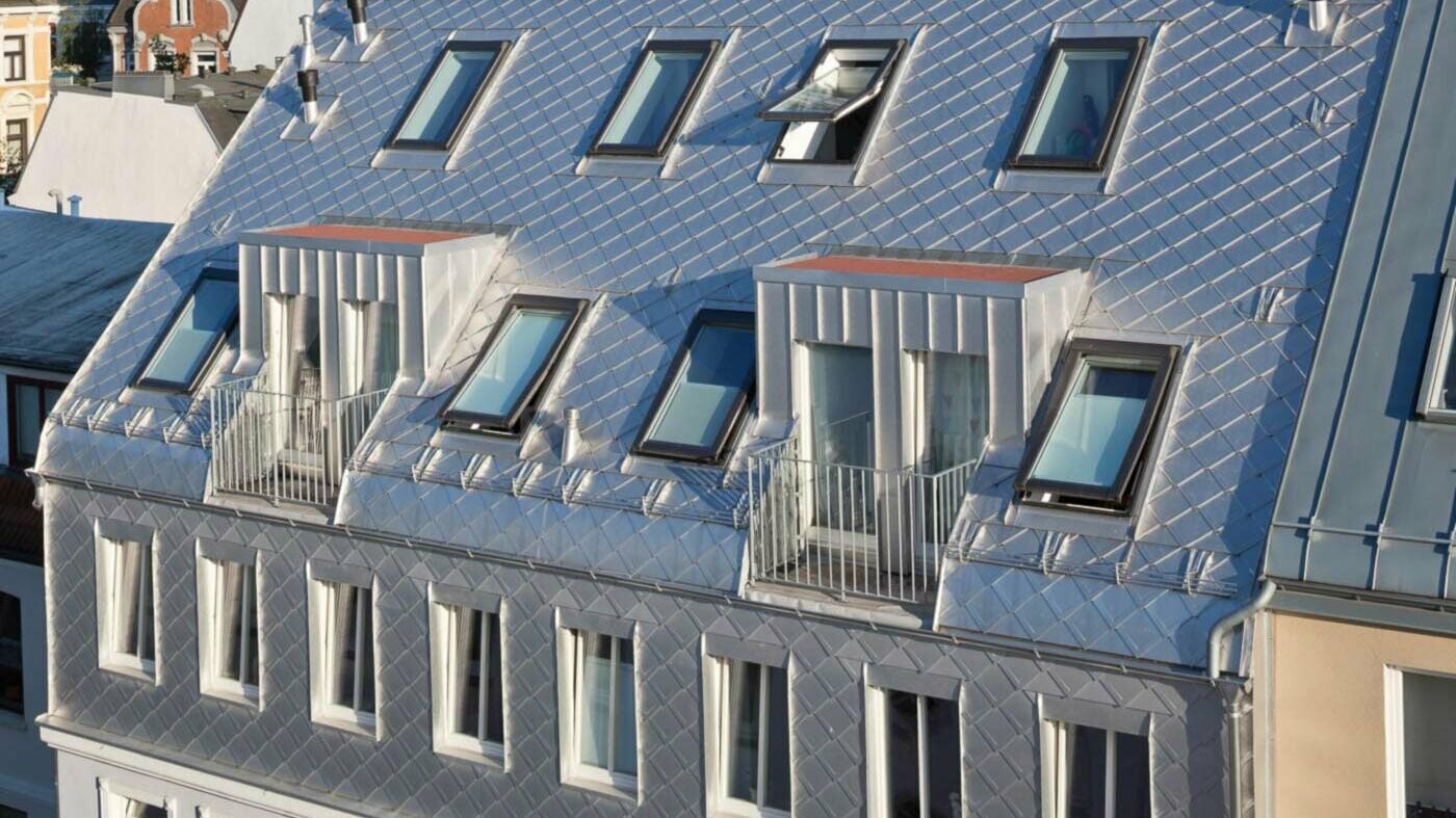 Blankt aluminium-sicksackmönstrat tak vid vindsombyggnad med många takfönster
