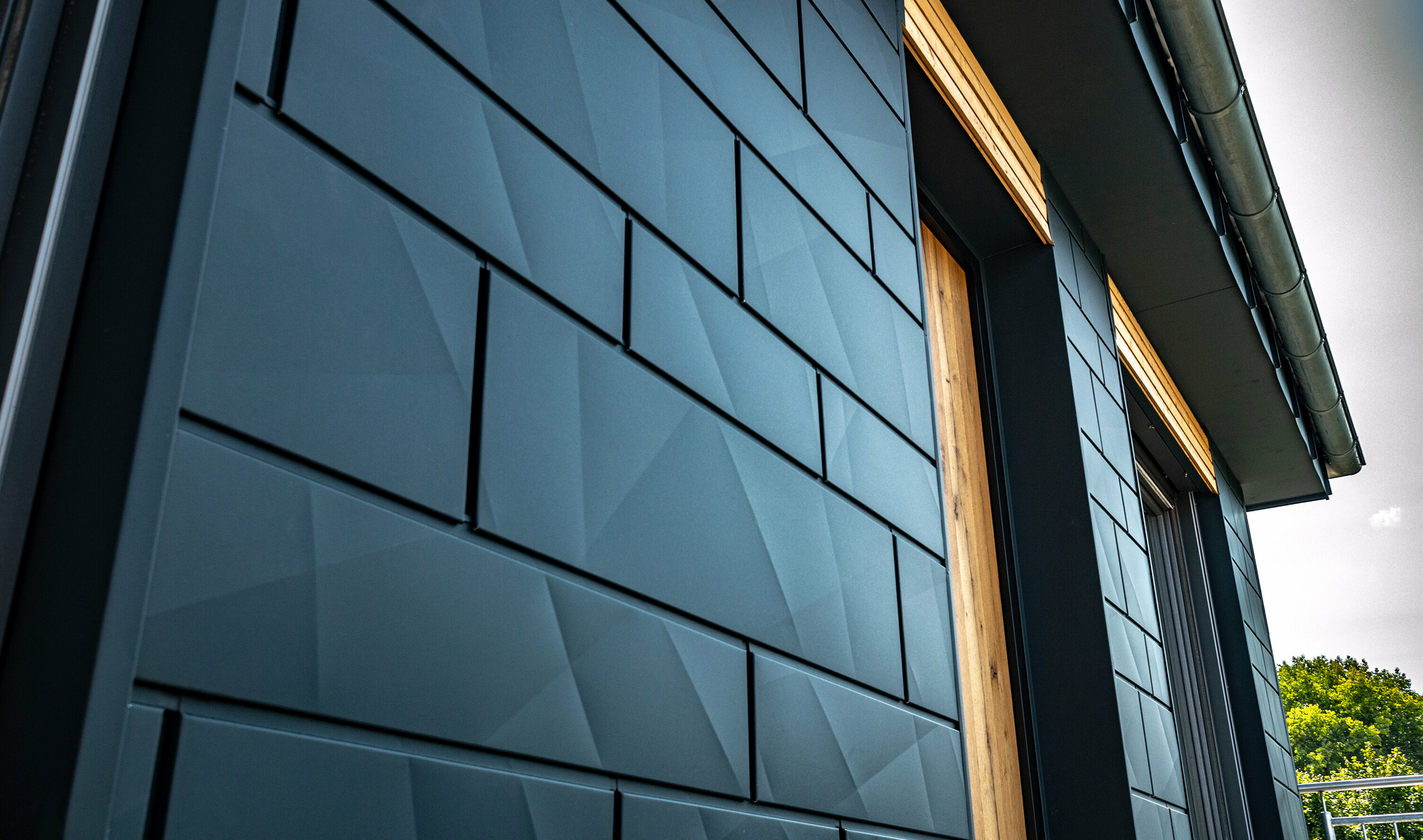 Fasad med PREFA Siding.X i antracit med balkongdörrar och stora glaspartier blandade med en träfasad.