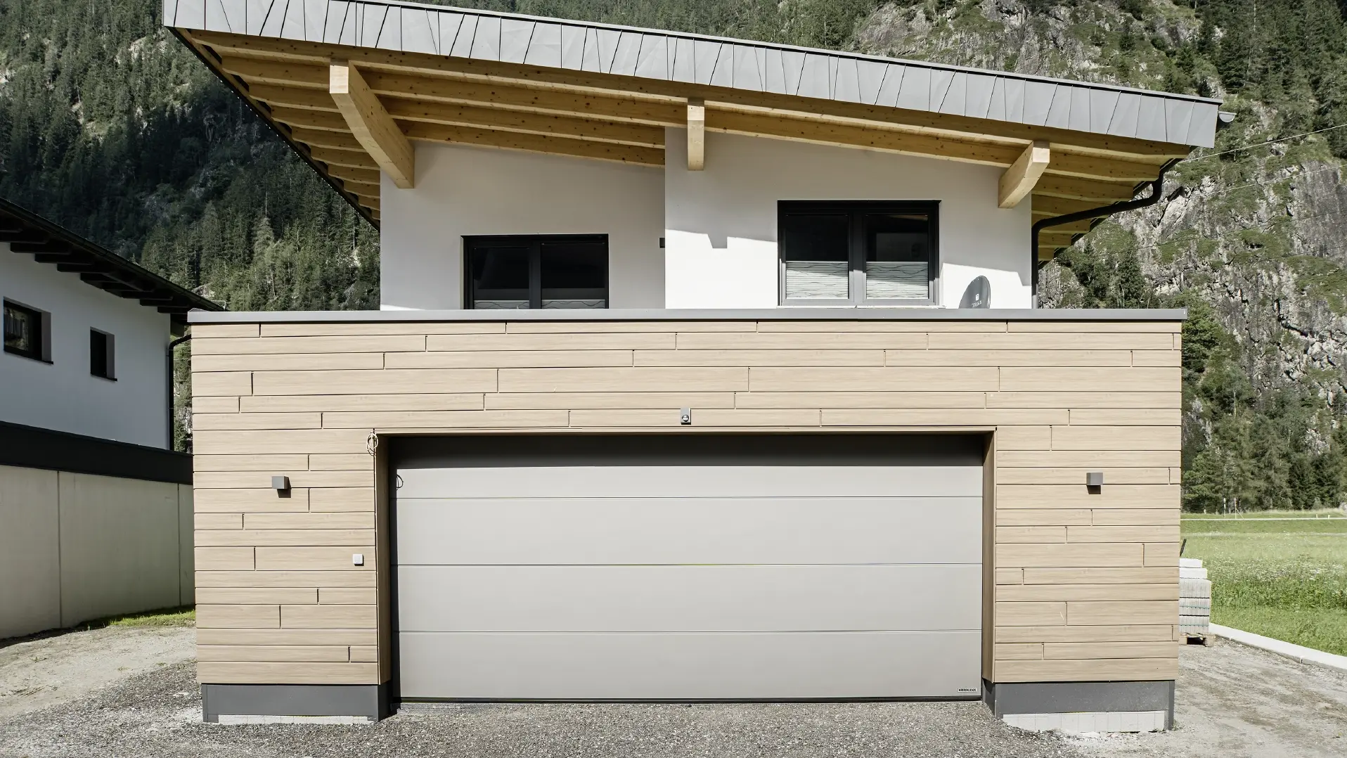 Modernt nybygge med pulpettak och speciell beklädnad på hängskivan, Garage med platt tak och med aluminiumfasad i valnötsbrun kulör från PREFA. Sidings är monterad horisontell och med olika byggbredder.