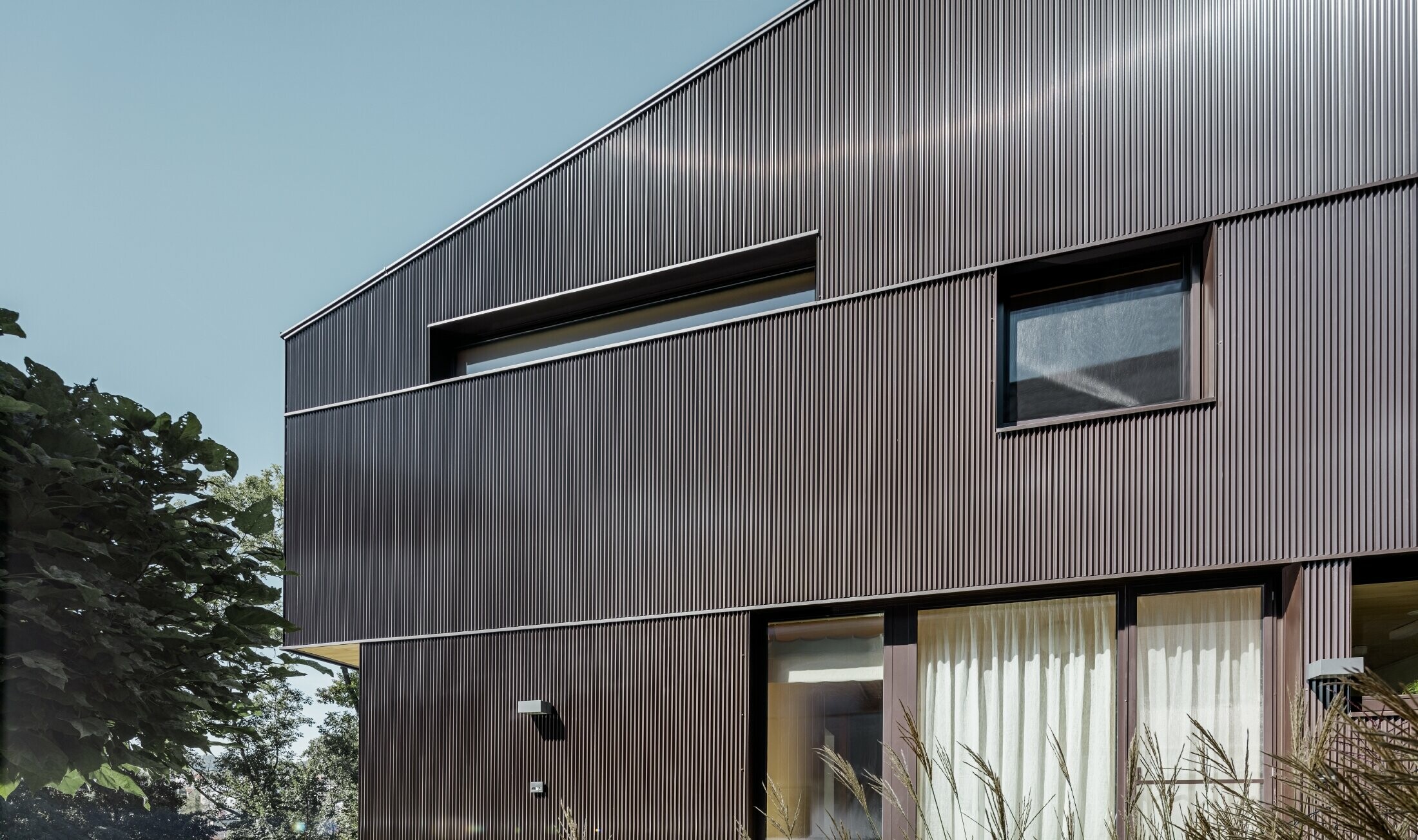 Modernt fristående hus med fasadbeklädnad från PREFA - brun sicksackprofil.