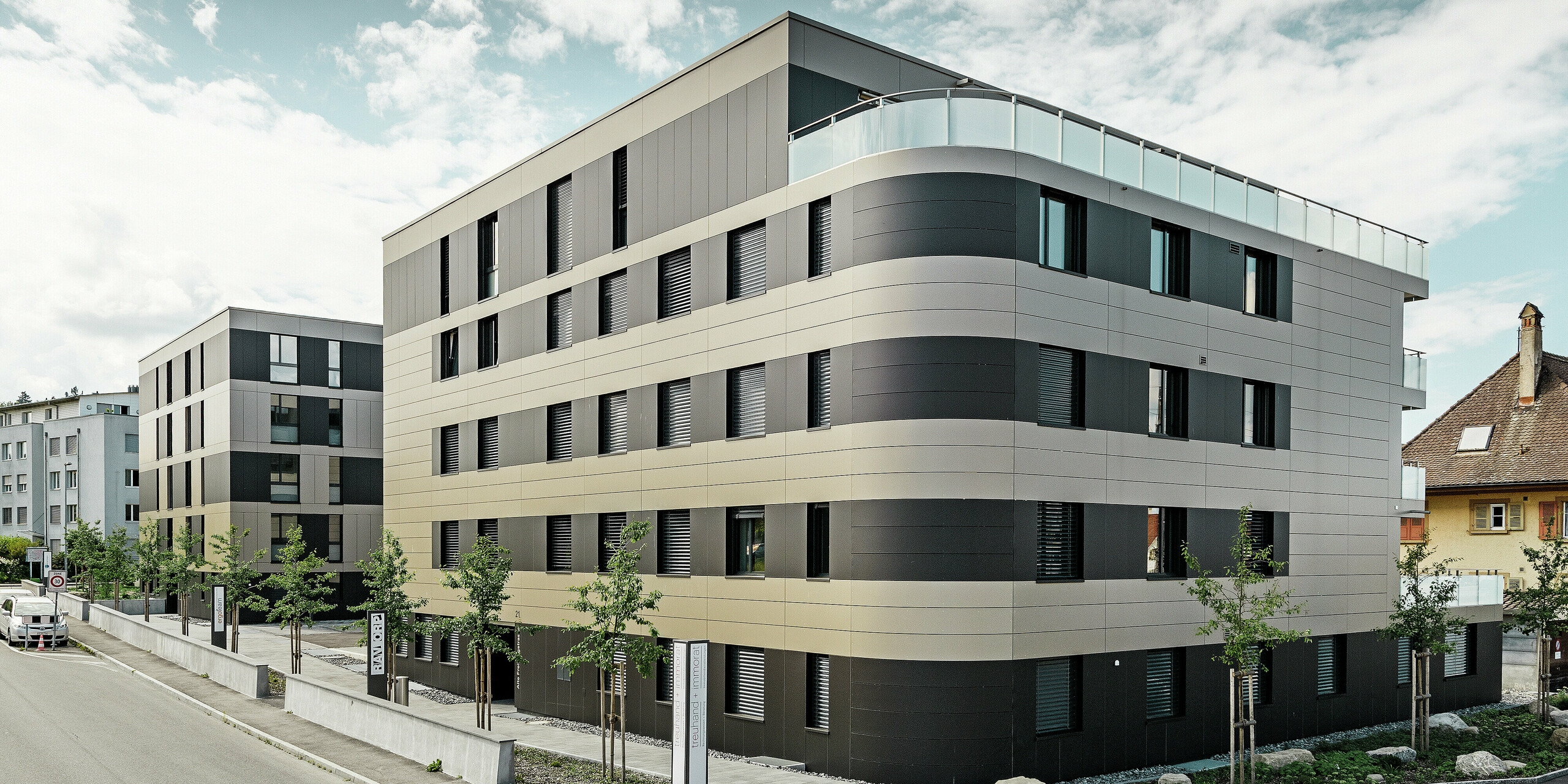 fyrkantig bostadsbyggnad med en aluminiumfasad i brons med svartgråa element