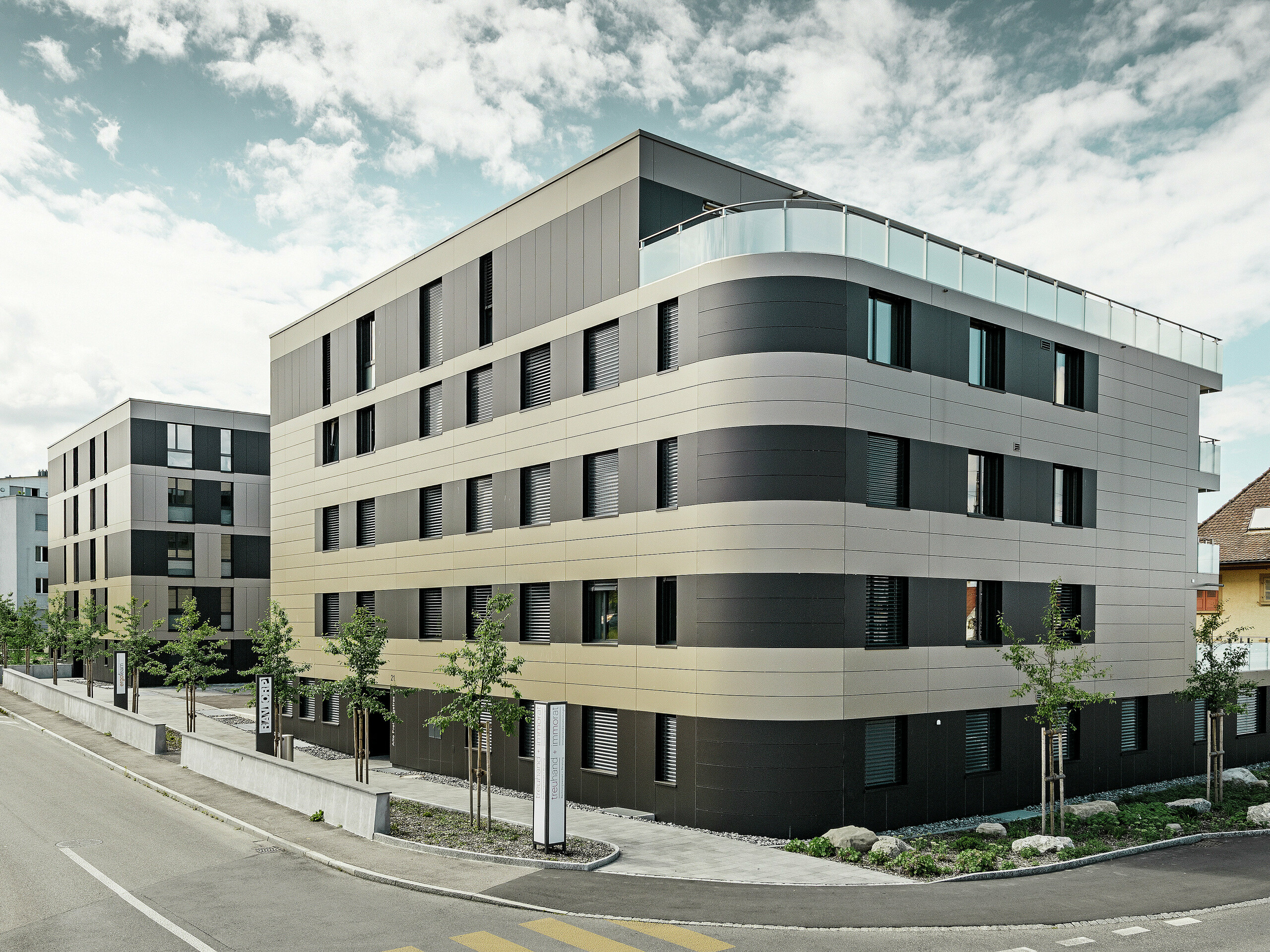 fyrkantig bostadsbyggnad med en aluminiumfasad i brons med svartgråa element