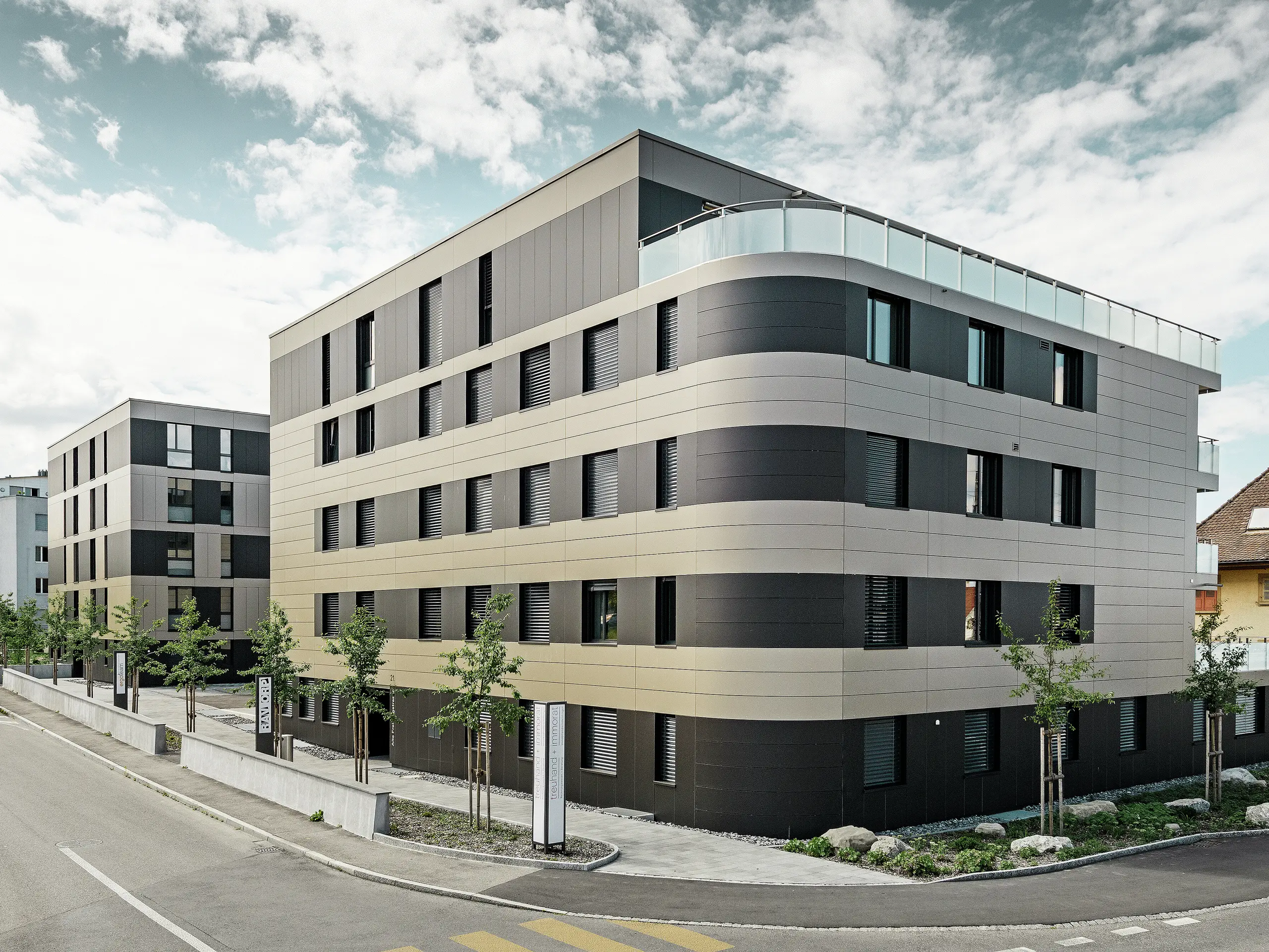 fyrkantig bostadsbyggnad med en aluminiumfasad i brons med svartgråa element