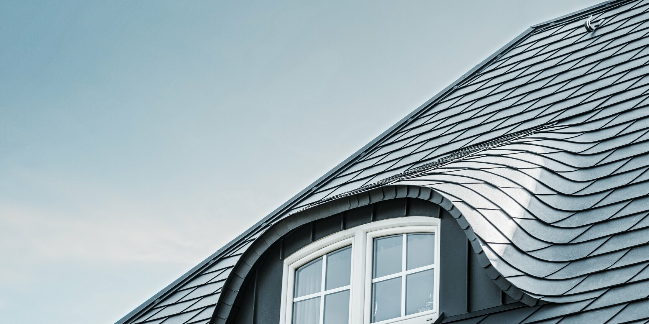 nyrenoverat tak med böjd takkupa med fönster intäckt med aluminiumshingel från PREFA i P.10 antracit 