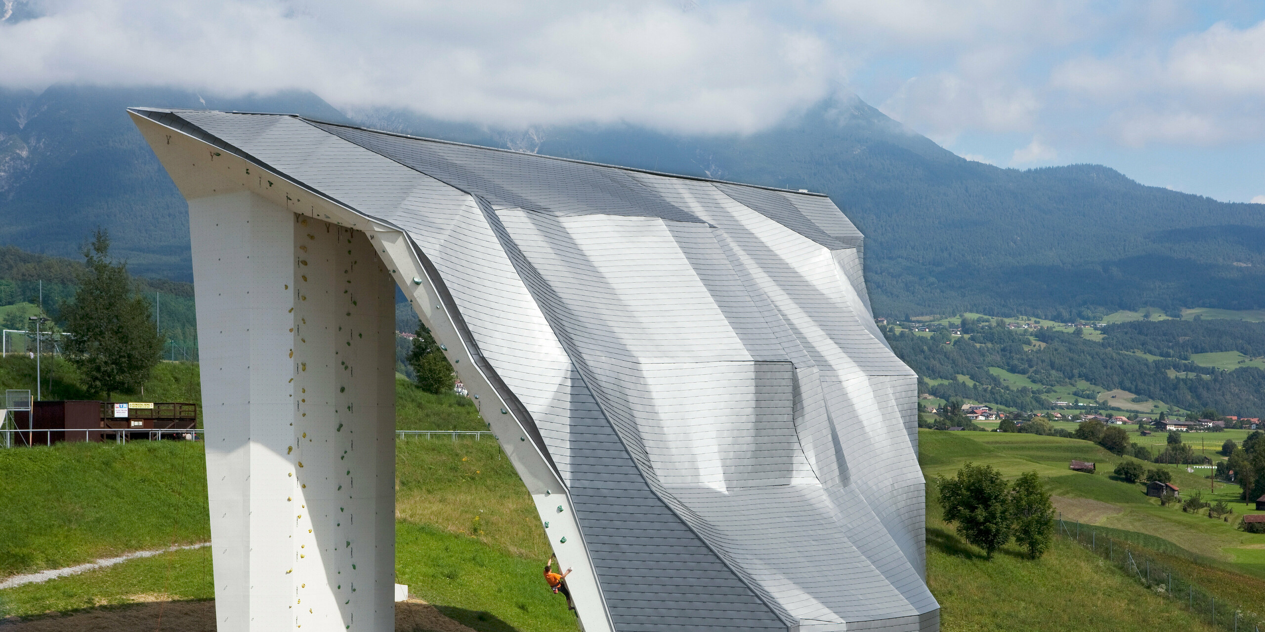 Vogelperspektive auf den Kletterturm Imst mit Aluminiumdach bzw. -fassade aus PREFA Dachschindeln in Silbermetallic und Bergpanorama im Hintergrund