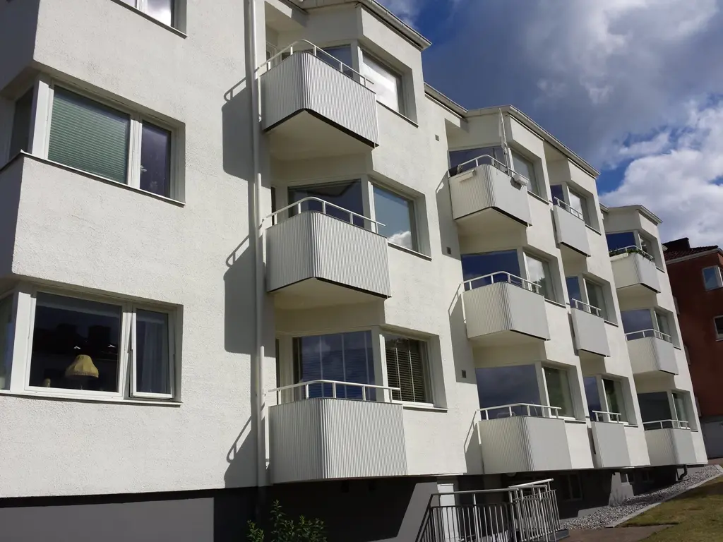 Flerfamiljshus med flera balkonger klädda med desertbeige Alustucco, vars ljusa färg harmoniserar med den vita fasaden.