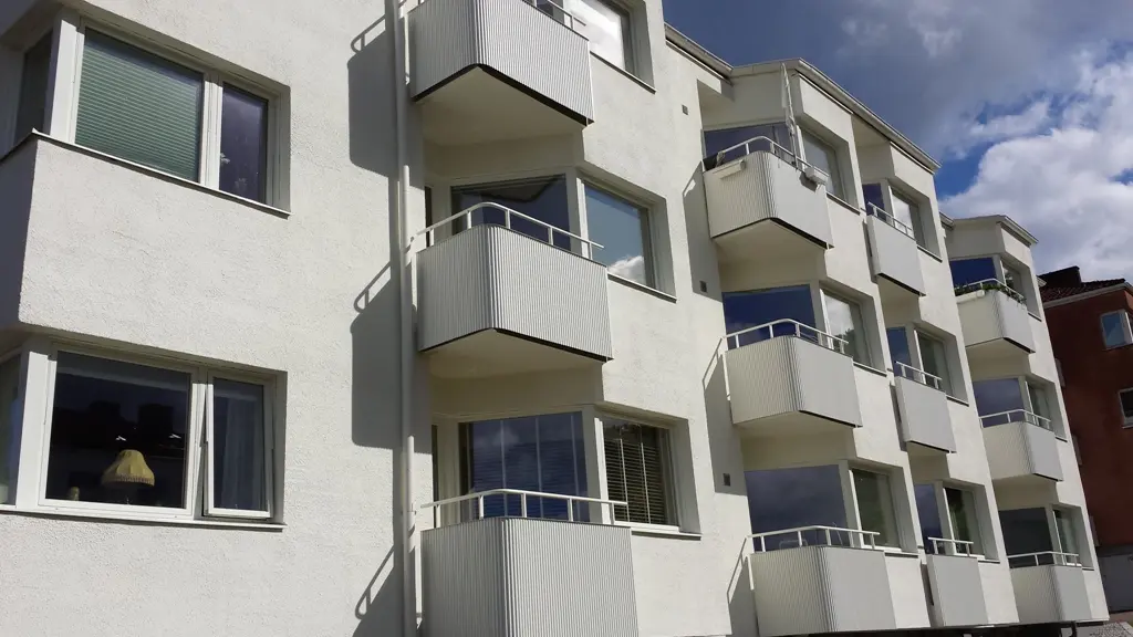 Flerfamiljshus med flera balkonger klädda med desertbeige Alustucco, vars ljusa färg harmoniserar med den vita fasaden.