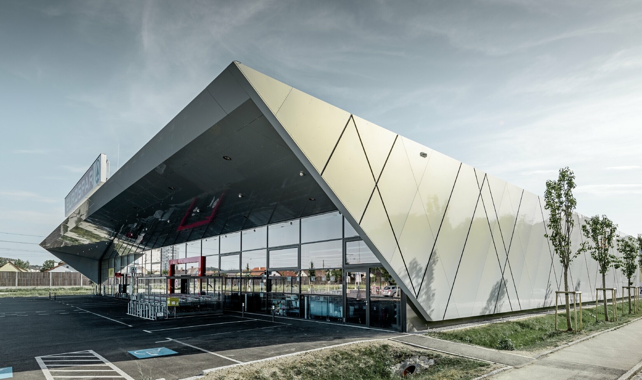 Ingången till den nya Eurospar filialen i Wels med den moderna fasadpanelen från PREFA i silverguld. Fasaden av aluminiumkomposit skimrar i solen i varierande färger beroende på betraktningsvinkeln.