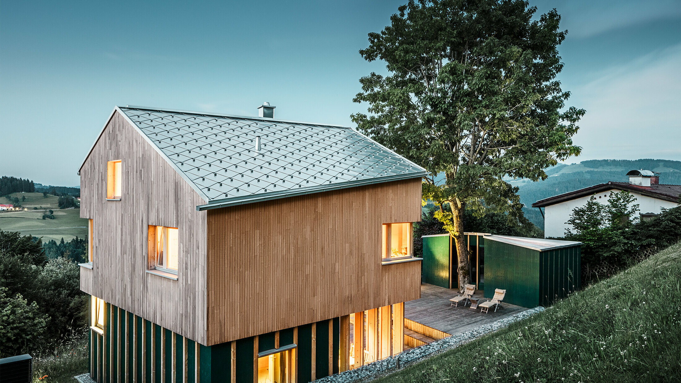 Nybyggt enfamiljshus med träfasad och naturblankt PREFA-tak i rombform