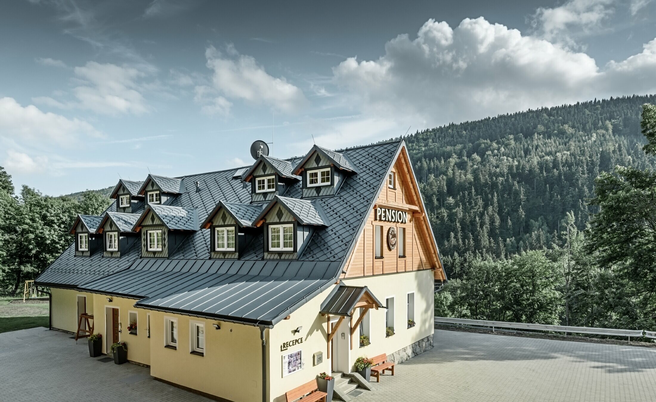 Pensionat i Tjeckien med brant tak och många takkupor täckta med aluminiumtak från PREFA, sicksackmönstrat rombtak med snörasskydd