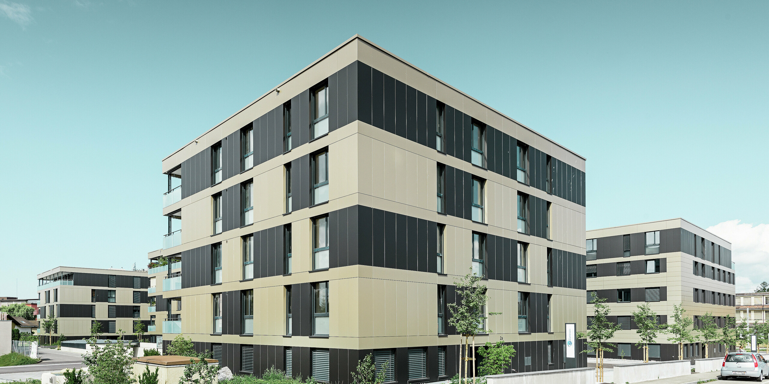 fyrkantig bostadsbyggnad med en aluminiumfasad i brons med svartgråa element