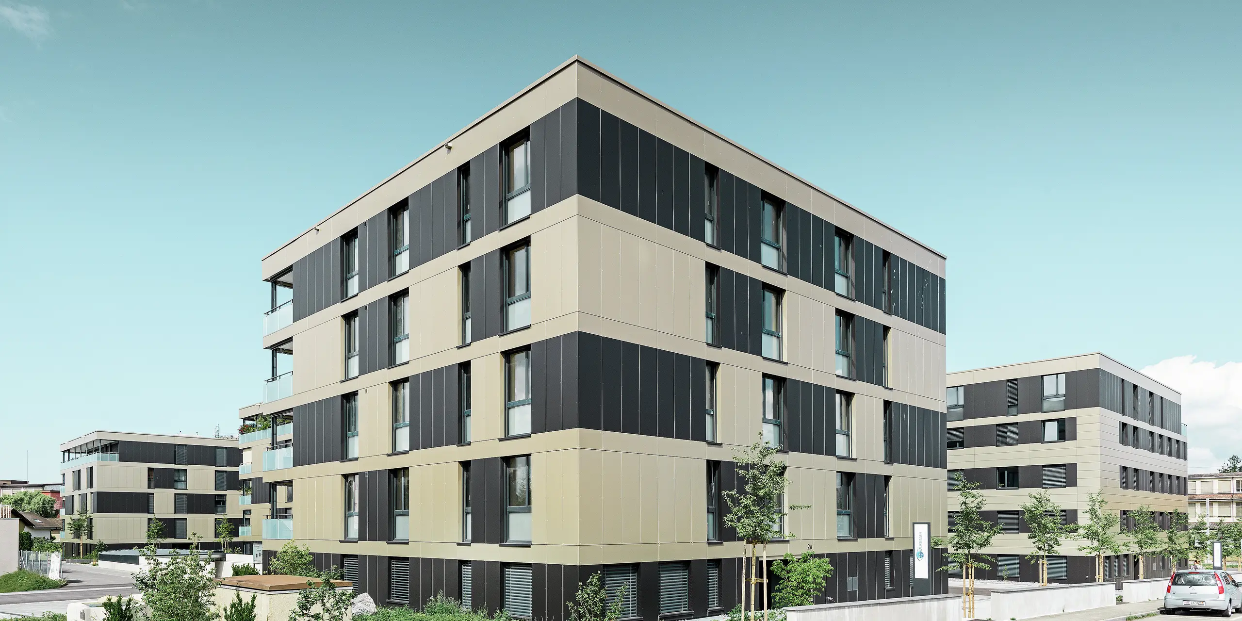 fyrkantig bostadsbyggnad med en aluminiumfasad i brons med svartgråa element