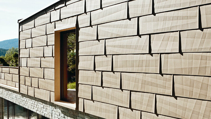 På denna ytterfasad har PREFA fasadpanel FX.12 i P.10 sandbrun kombinerats med en stenfasad på källarplanet.