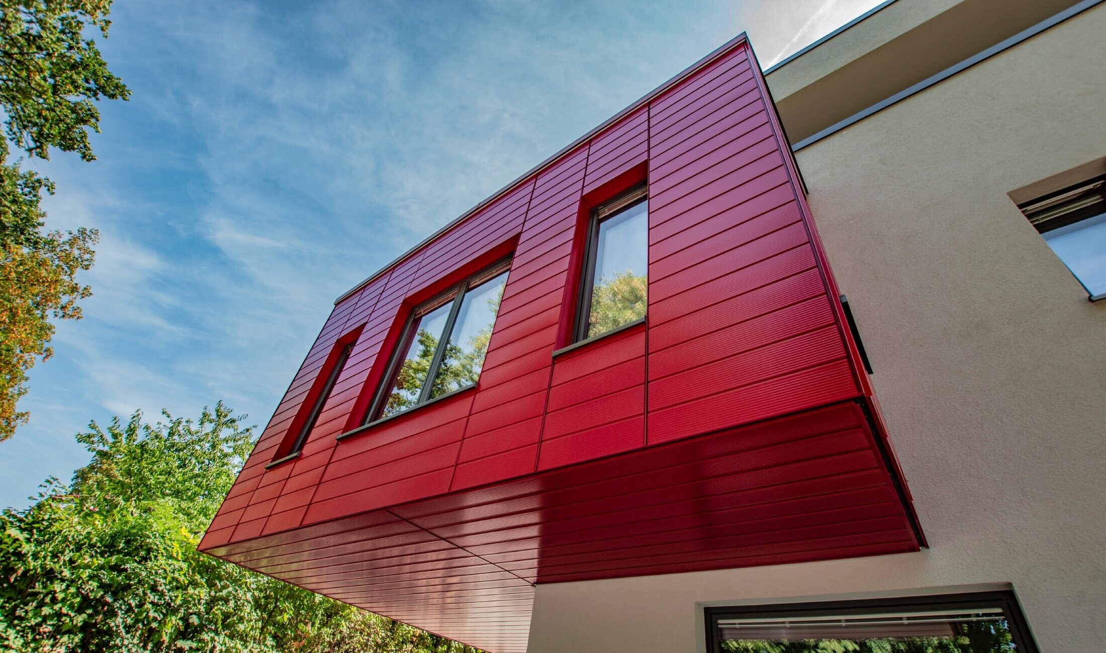 Burspråk klätt med PREFA vågrätt linjerad fasadpanel i rubinrött.