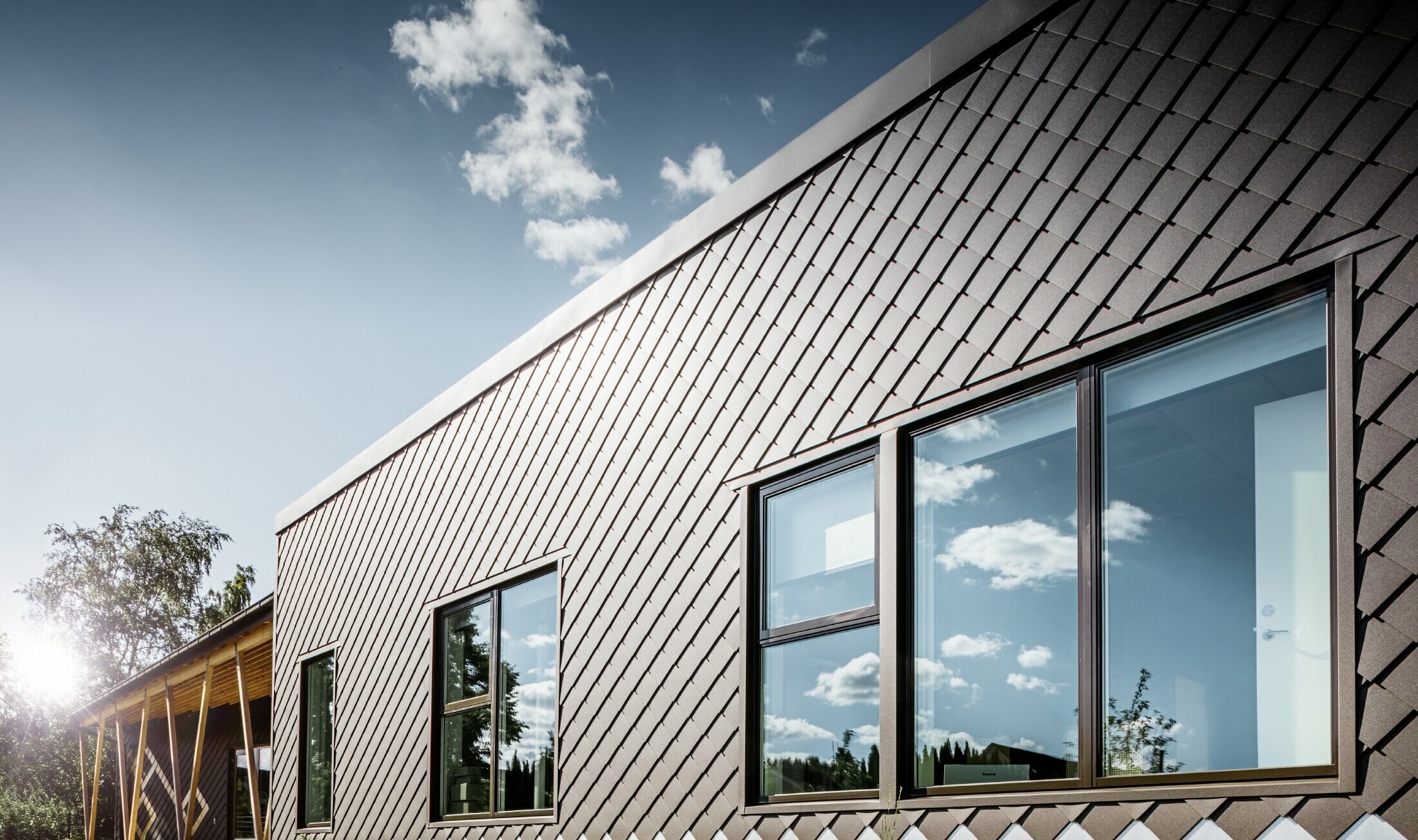 Denna bild på en förskola i Stockholm visar den nya fasaden med stora fönsterpartier och flackt tak. Ytterfasaden täcktes med fasadromb 20 × 20 i brun.