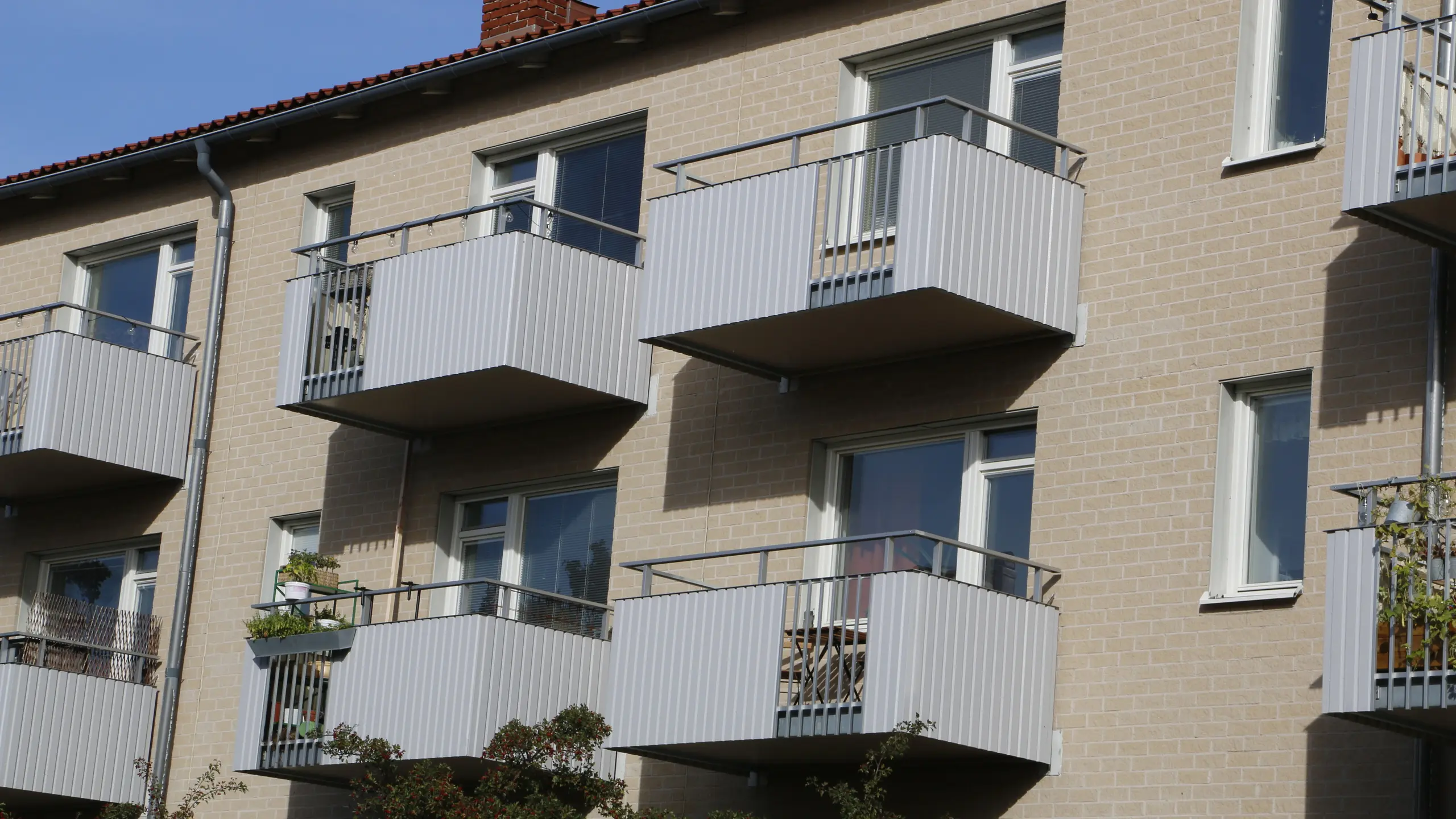 Renoverade klassiska balkonger på ett flerfamiljshus, inklädda i ljusgrå Alustucco som ger fasaden ett stilrent uttryck.