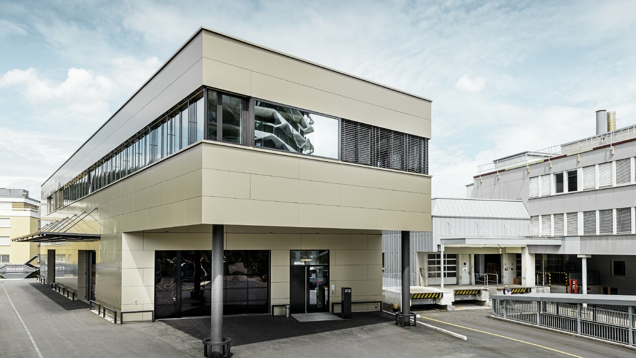 Modern tillbyggnad med verkstad och kontor hos Guggisberg Dachtechnik med PREFA aluminiumkompositskiva i brons