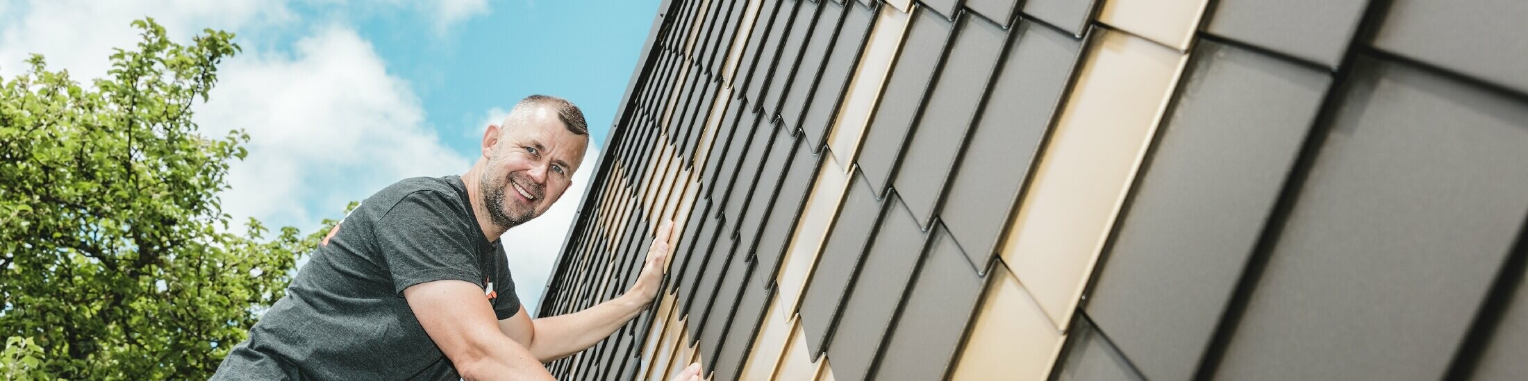 PREFA Handwerker in Ihrer Nähe an einer Fassade mit PREFA Wandrauten in Braun und Mayagold.