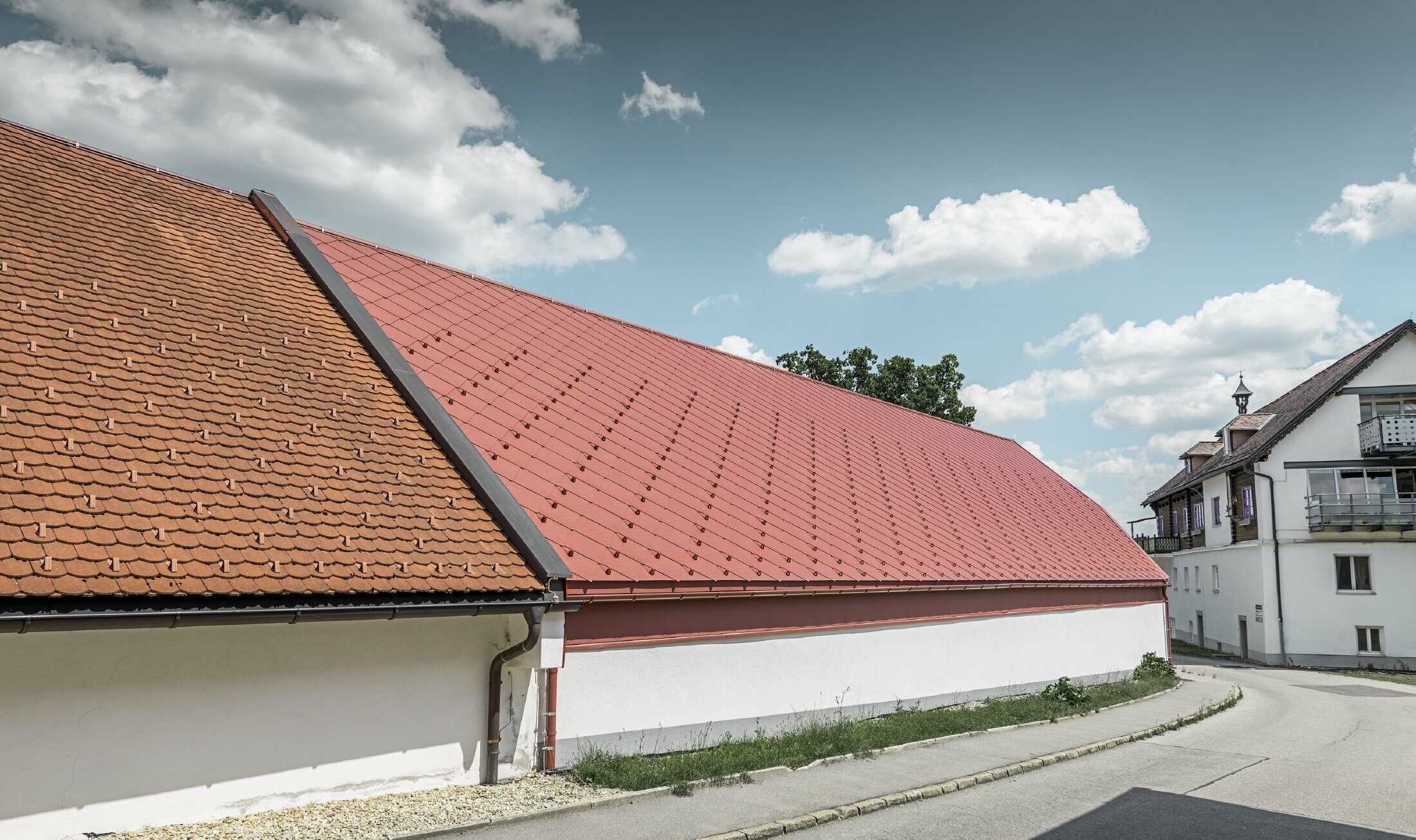 Exteriörbild av Kerzenwelt i Schlägl. Taket täcktes med den storskaliga aluminiumromben 44 x 44 från PREFA i oxidrött.