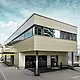 Modern tillbyggnad med verkstad och kontor hos Guggisberg Dachtechnik med PREFA aluminiumkompositskiva i brons