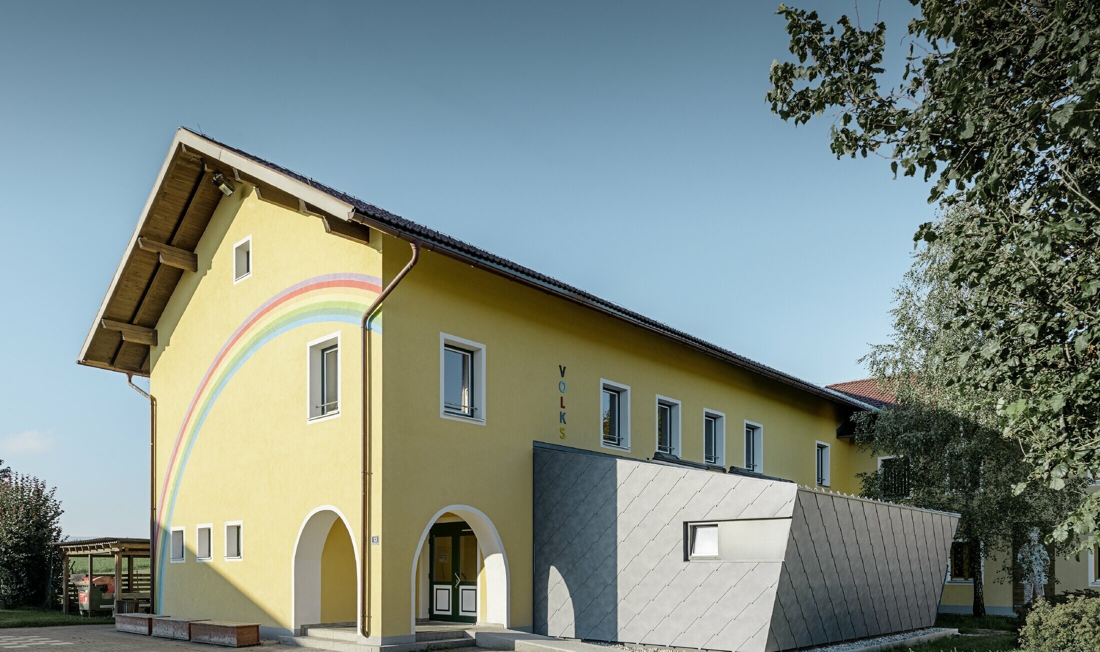 Tillbyggnad på en folkskola täckt med tak- och väggromber av aluminium från PREFA i stengrått