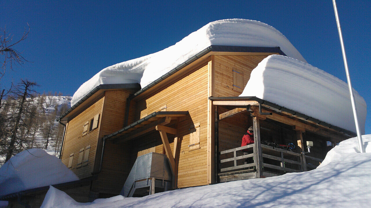 Stugan Capanna Buffalora med flera centimeter snö på taket.  