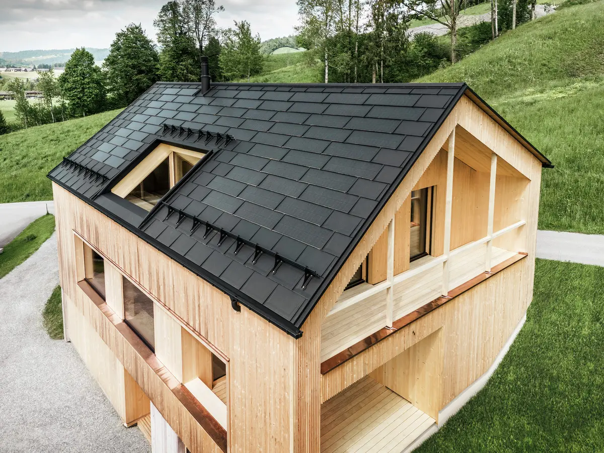 Enfamiljshus i den österrikiska staden Egg med PREFA solpanel och takpanel R.16 i svart i kombination med en träfasad.