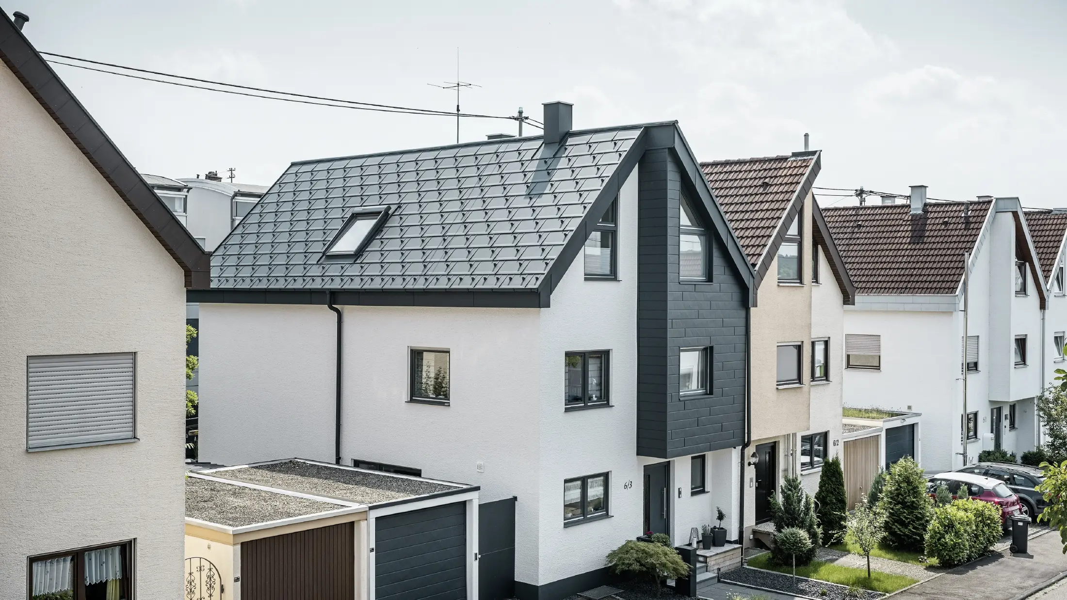 Ena hälften av ett dubbelhus har redan genomgått renovering och fått en ny, vit putsfasad i kombination med en fasad med PREFA Siding.X i antracit. Taket täcktes med PREFA takplatta R.16. Takavvattningen sker via rektangulära rännor inklusive PREFA stuprör.