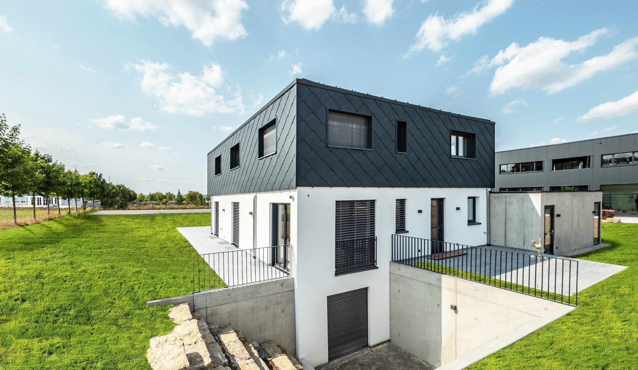 PREFA väggromber 44 × 44 i antracit med vitputsad fasad i en enkel nybyggnation med platt tak.