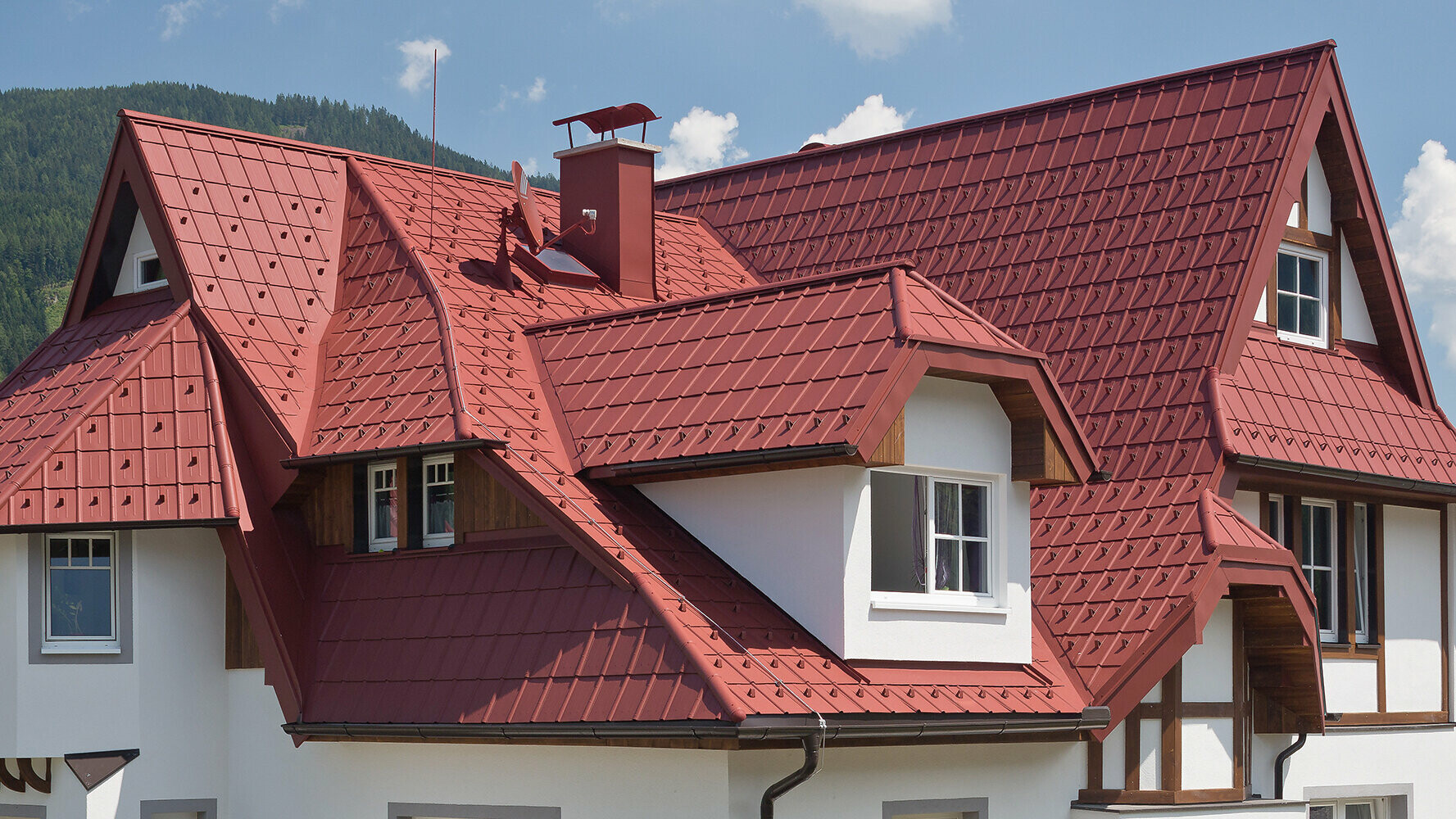 Taket på denna villa har många olika vinklar och vrår, detaljer och takkupor. Det täcktes med PREFAs takplattor i oxidrött.