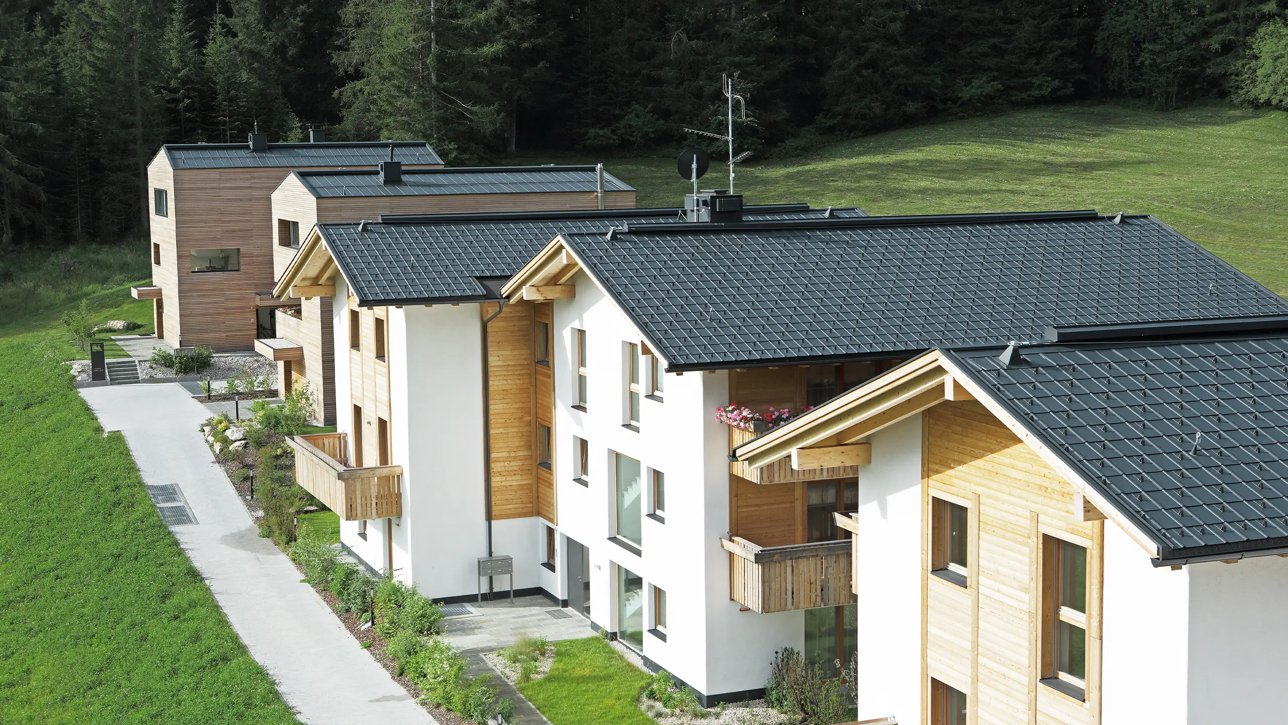 Foto av de fem bostadshusen i Corvara, täckta med PREFA takplatta och PREFALZ i antracit av stormsäkert aluminium