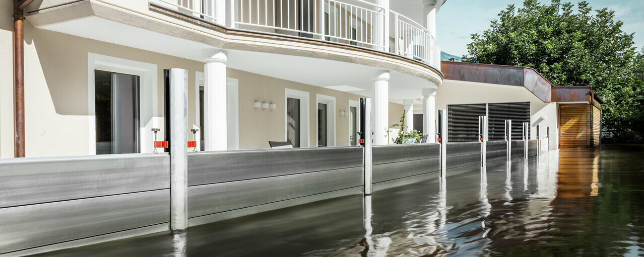 Bilden visar ett fristående hus med balkong. PREFA översvämningsskyddssystem skyddar huset från de redan stigande vattenmassorna.