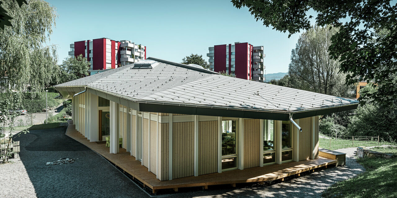 Förskola i enplansbyggnad med vertikal fasadpanel och aluminiumtak från PREFA (takromb) i ljusgrå